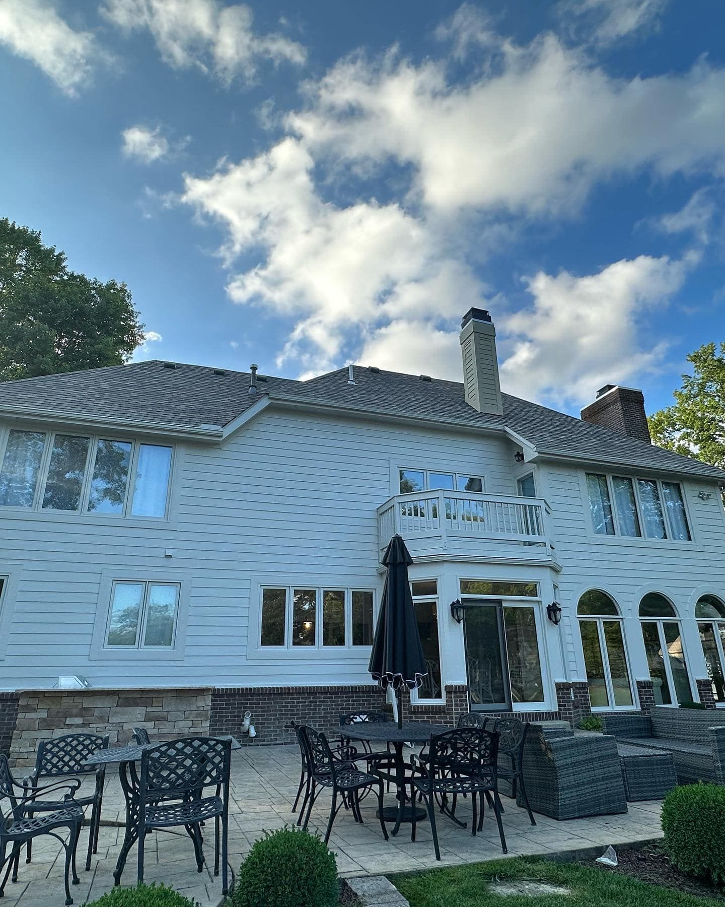 White house with patio furniture under a partly cloudy sky.