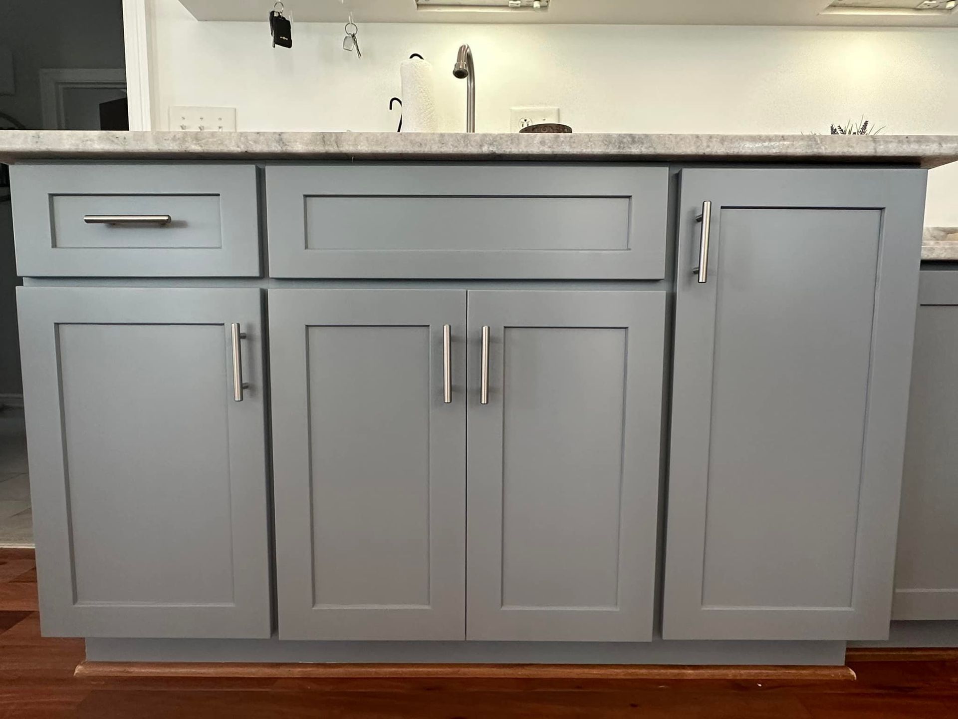 Gray kitchen cabinets with silver hardware and a light countertop.