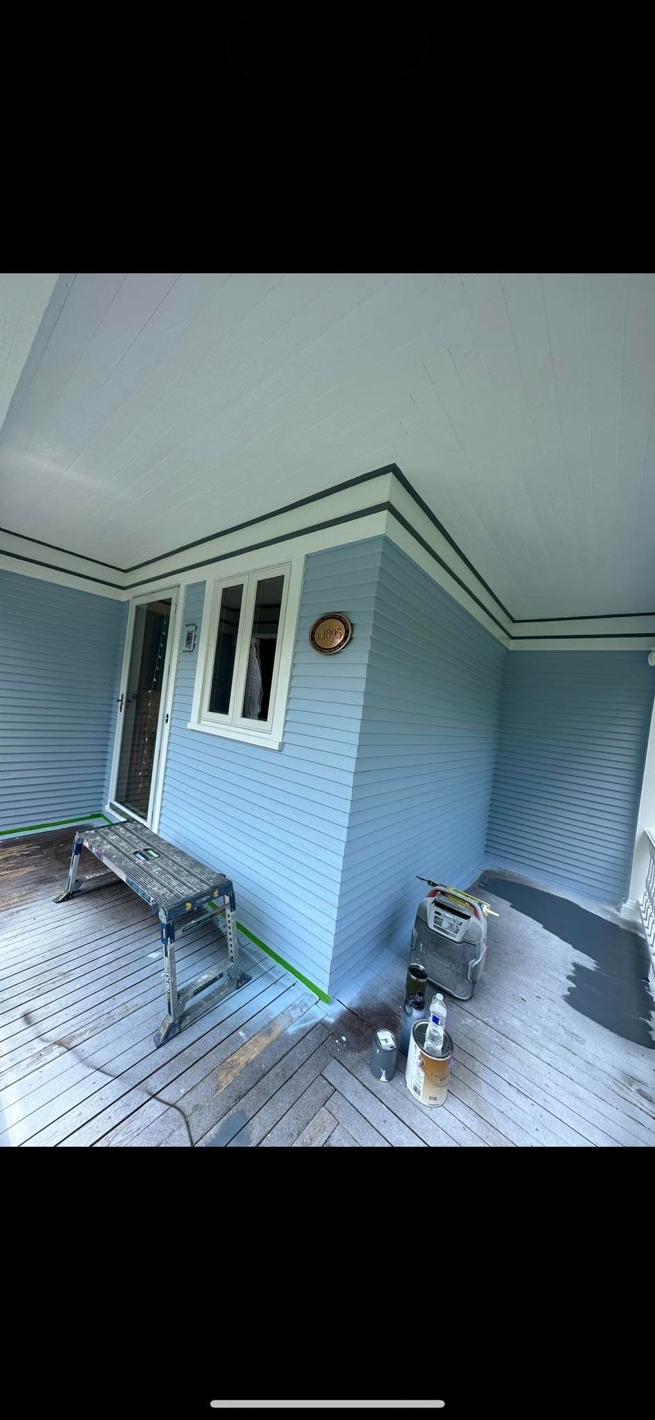 Porch with blue siding, white ceiling and trim, and tools.
