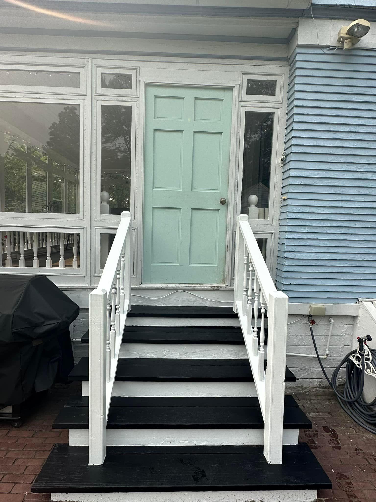 Blue door with white trim, accessed by several dark steps with white handrails.