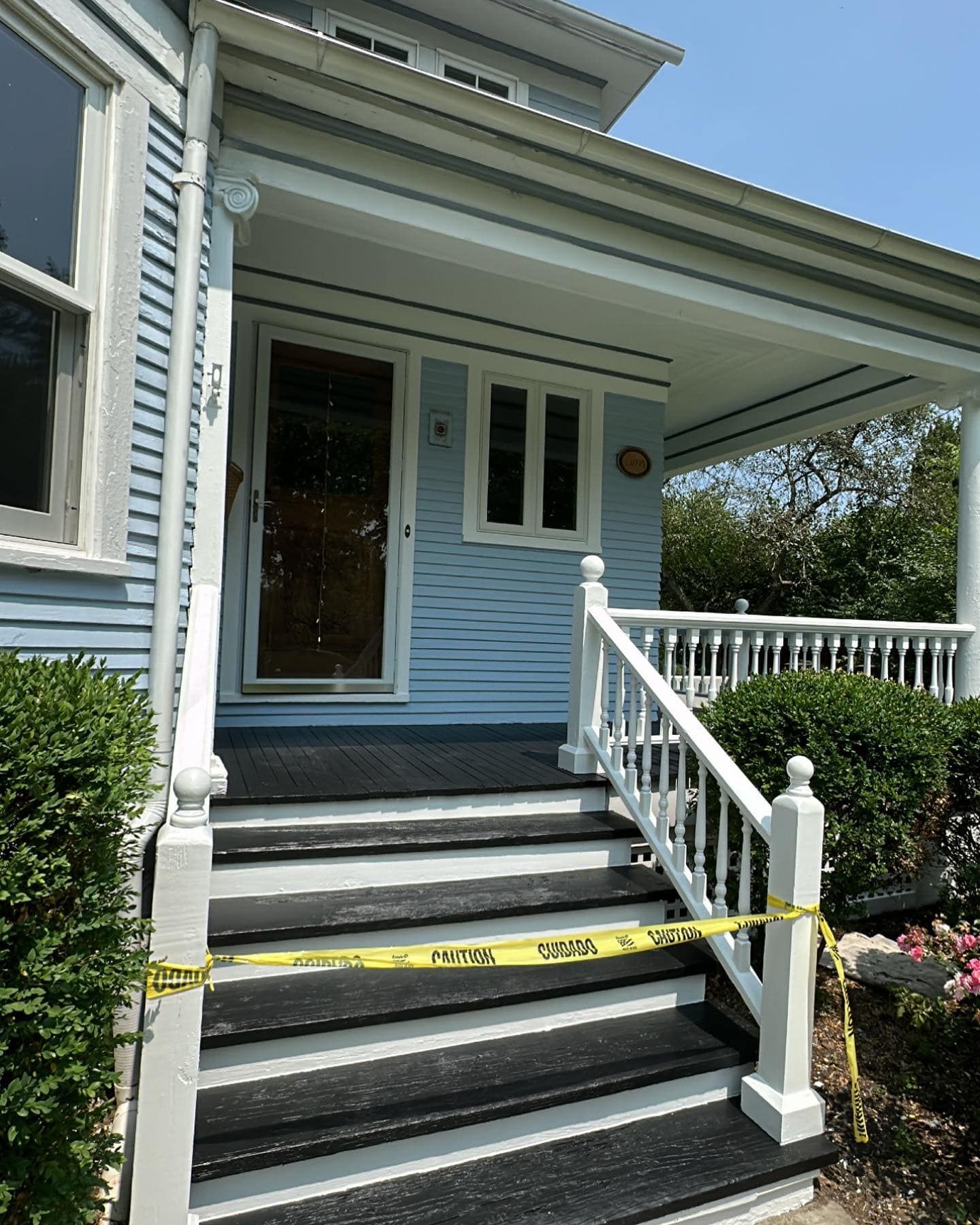 Blue house entrance with steps, yellow caution tape across steps.