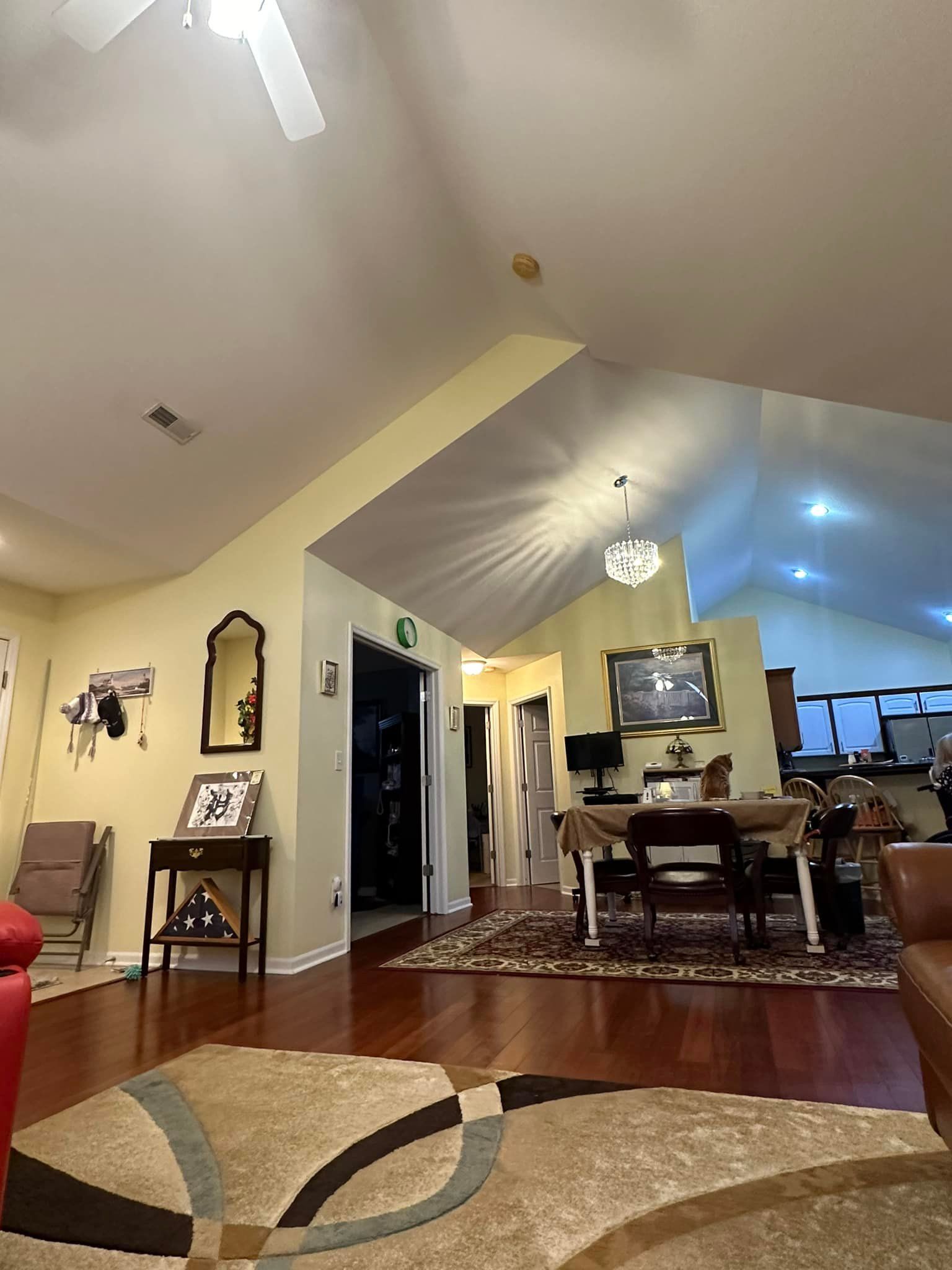 Living room with high ceilings, hardwood floors, rug, and dining table.