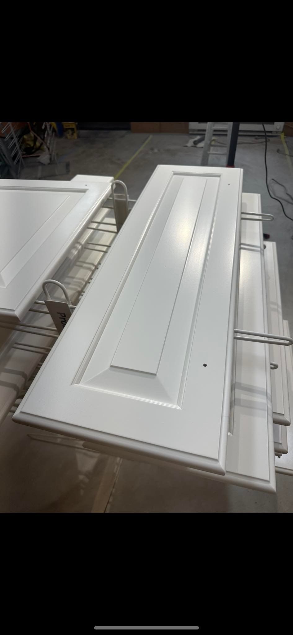 White cabinet doors on a rack in a factory setting.