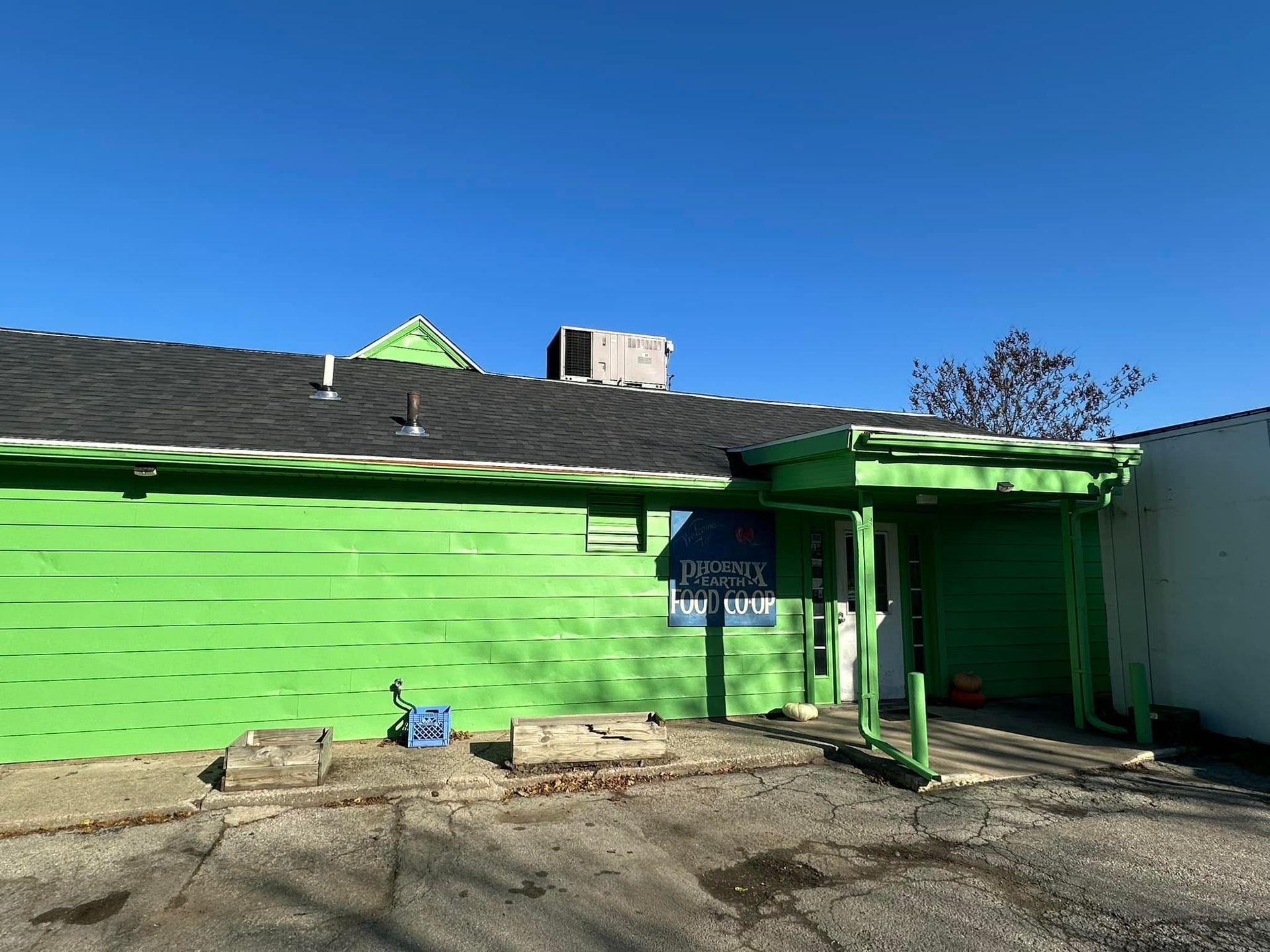 Bright green building with black roof, doorway, and sign. Blue sky above.