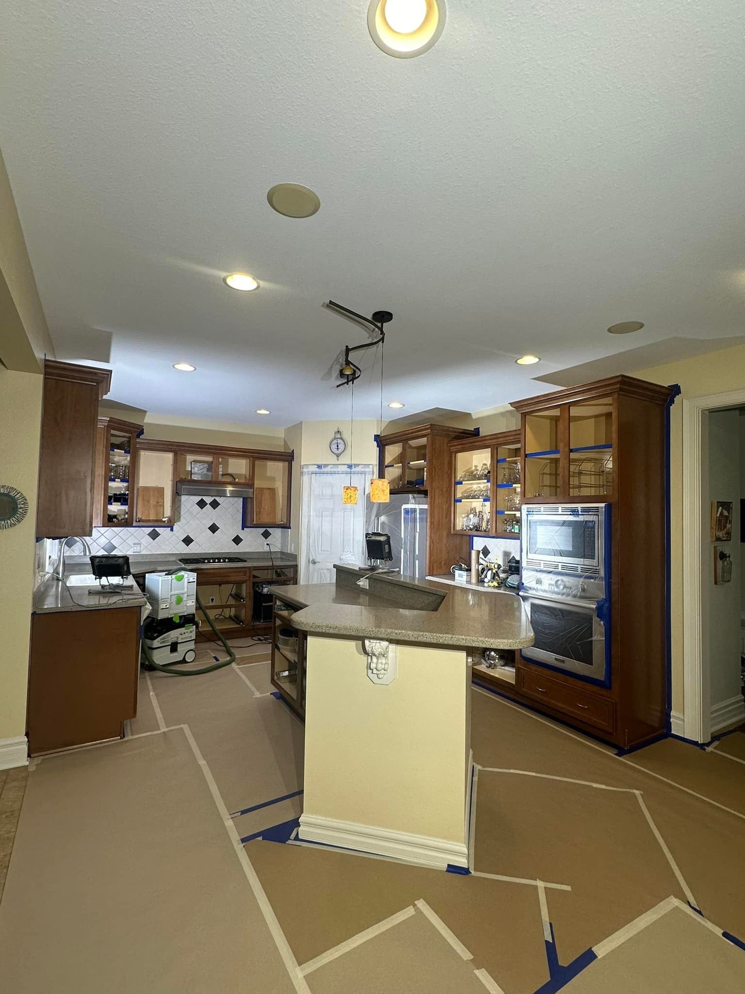 Kitchen with wood cabinets, island, and appliances. Protective paper covers the floor.