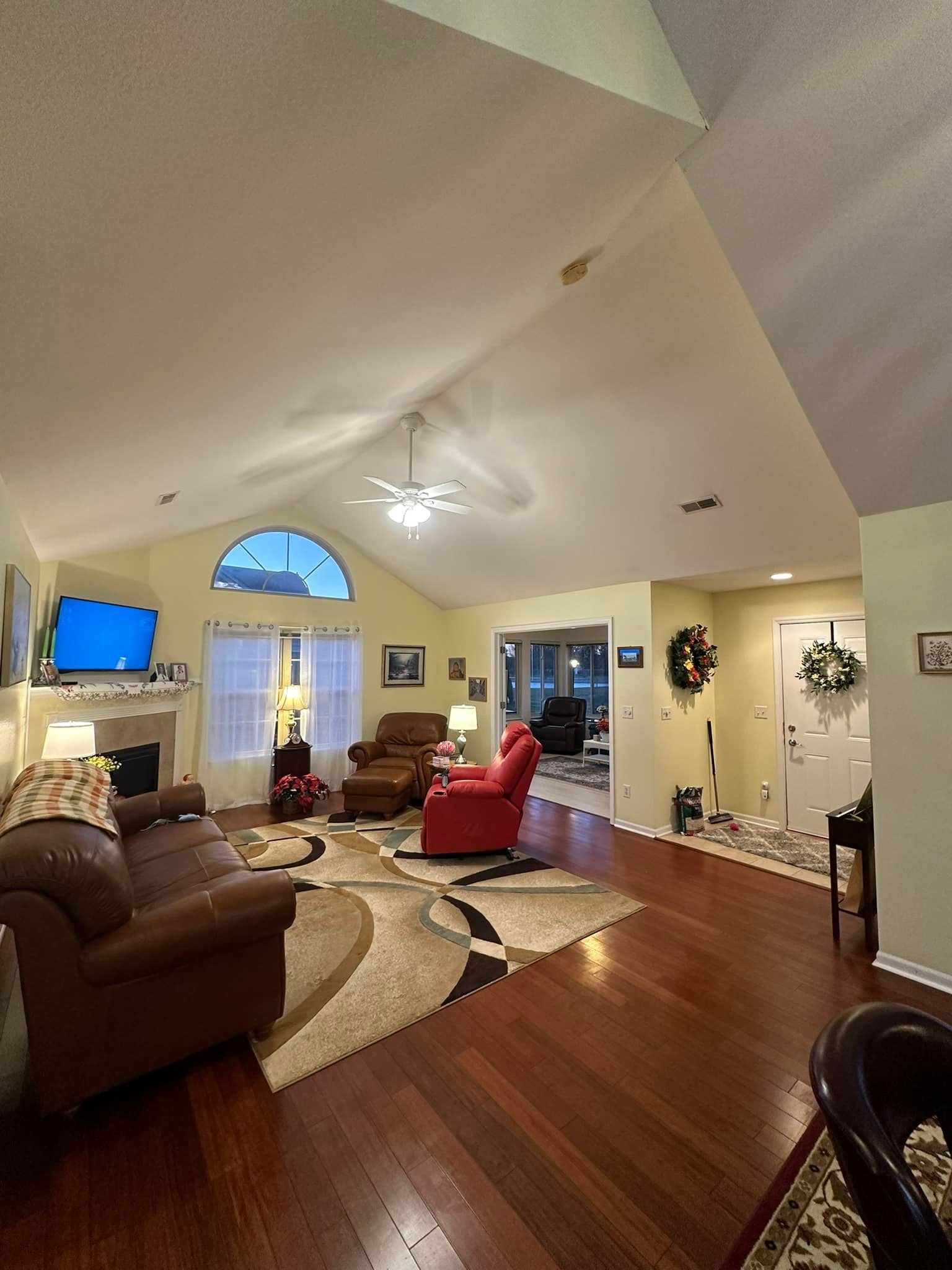 Living room with high ceilings, fireplace, furniture, and hardwood floors.