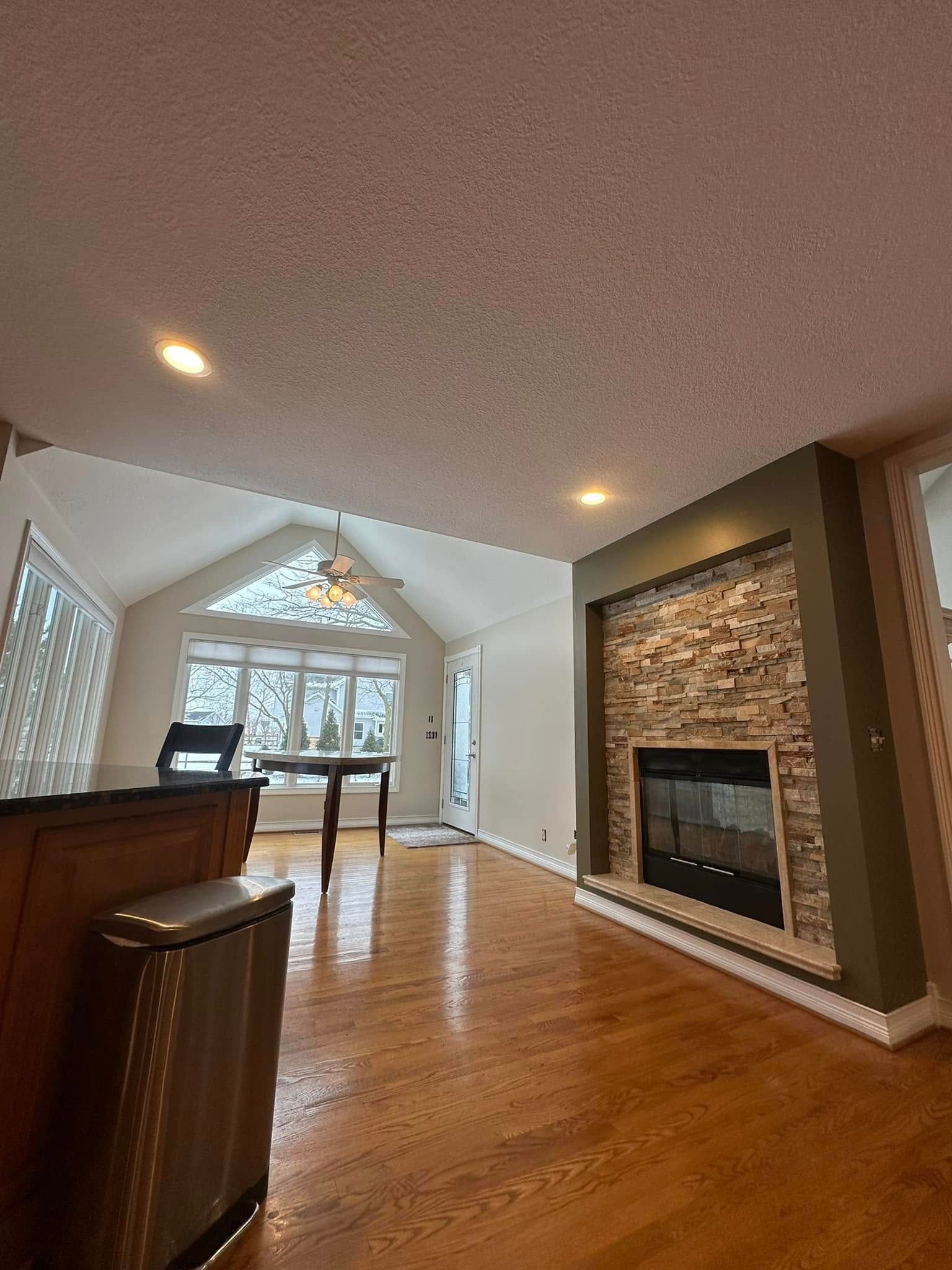 Living room with hardwood floors, fireplace, and large windows.