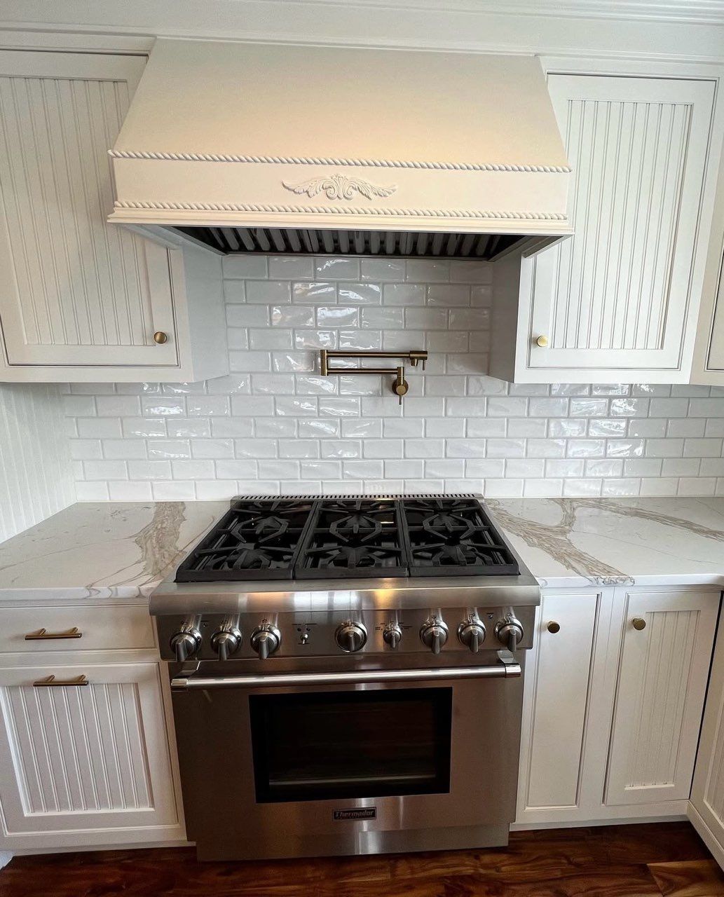 White kitchen cabinets with built-in microwave and oven, granite countertop, stainless steel appliances.