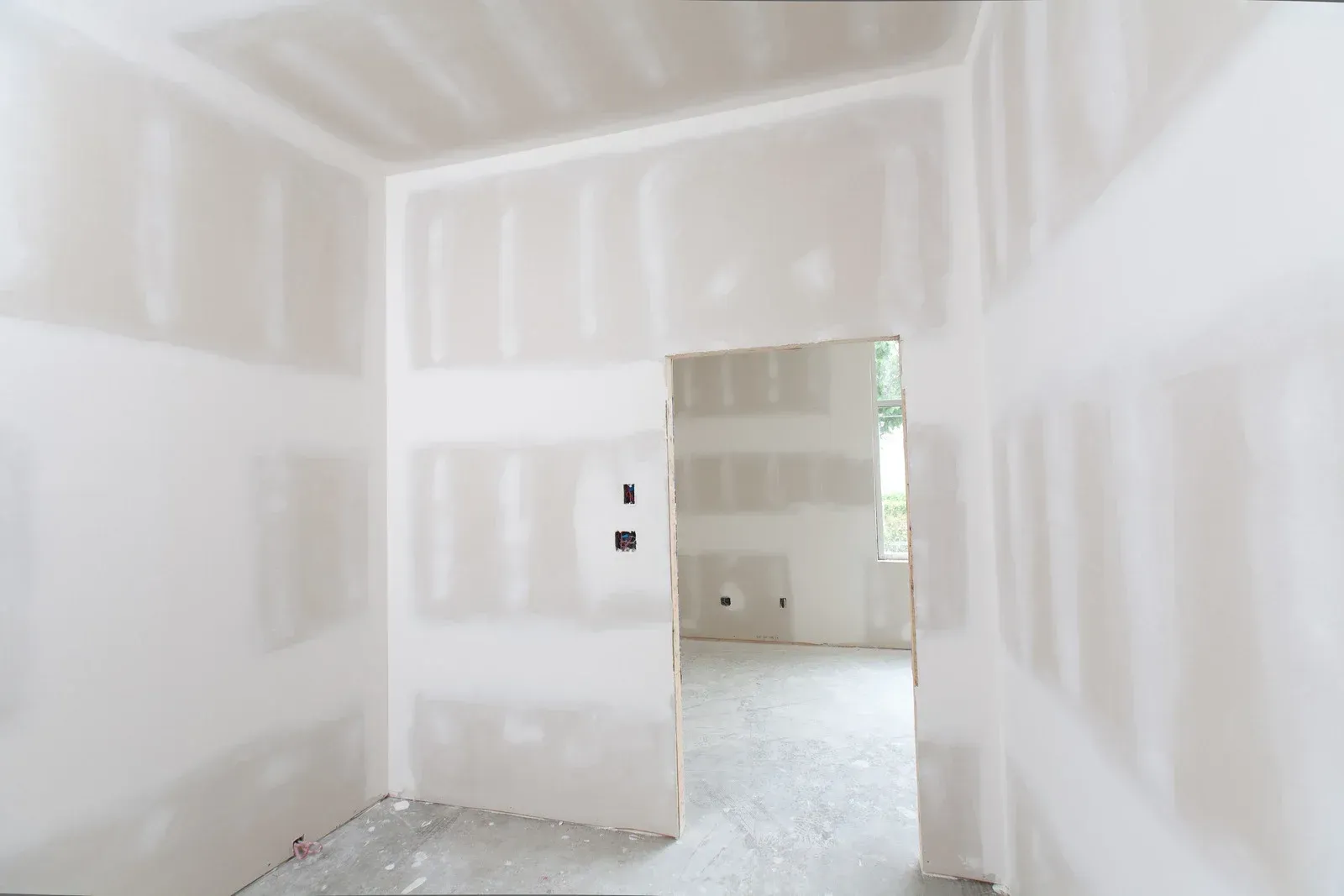 Interior room under construction, with drywall walls and doorway.