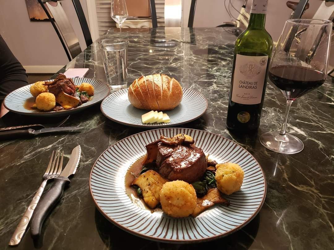 A bottle of wine is sitting on a table next to a plate of food.