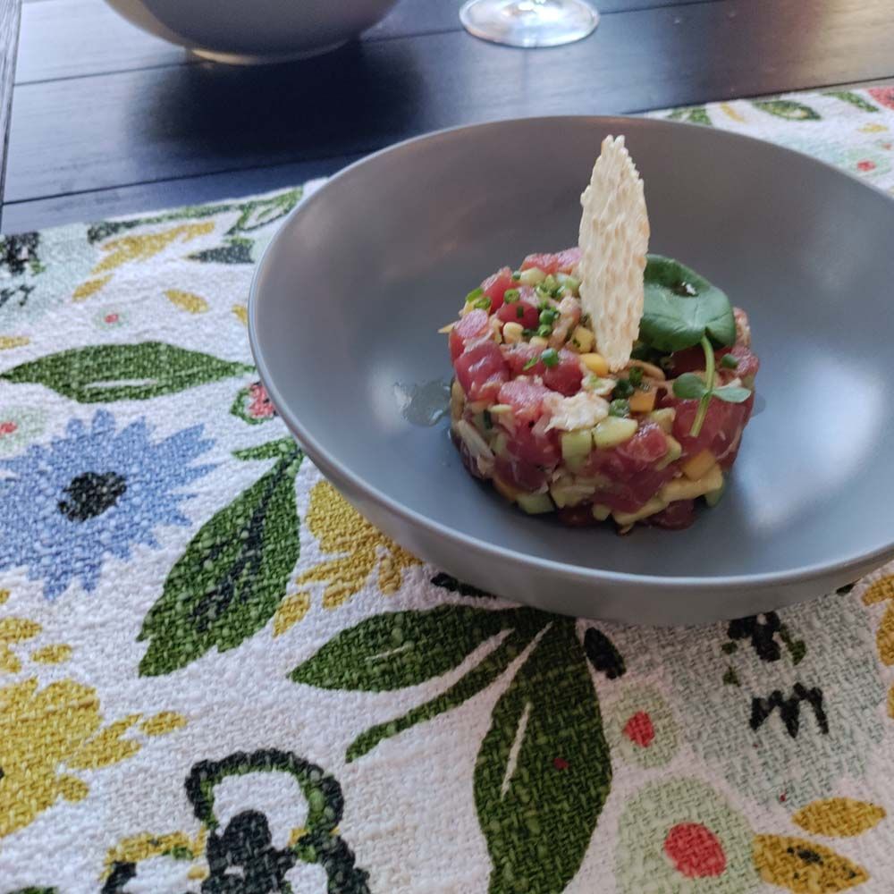 A bowl of food sits on a floral place mat