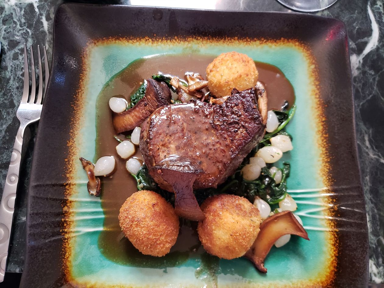 A bottle of wine is sitting on a table next to a plate of food.