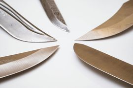 Four knives are arranged in a circle on a white surface