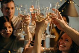 A group of people are toasting with wine glasses at a party.