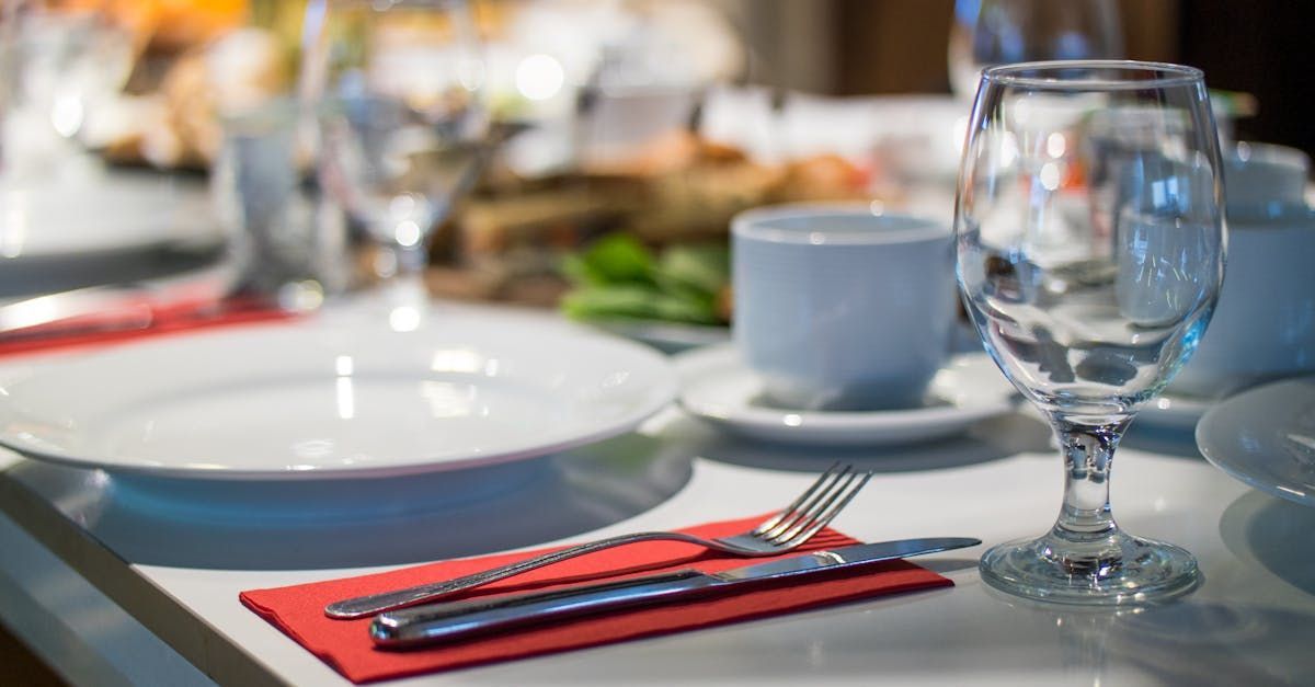 A table set for a meal with plates , utensils , and a wine glass.