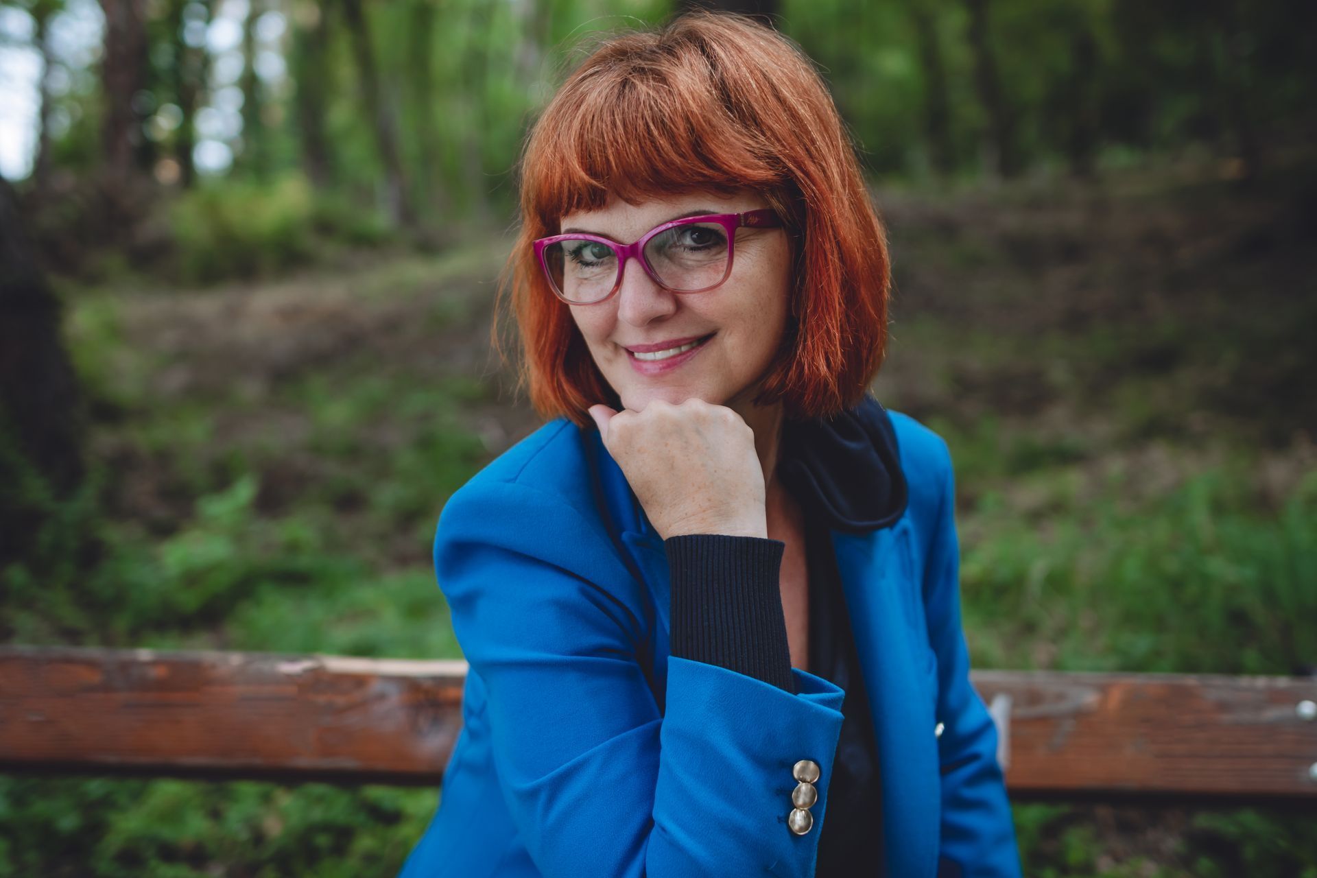 red hair women marketing consultant is sitting on the bench with hand below her chin