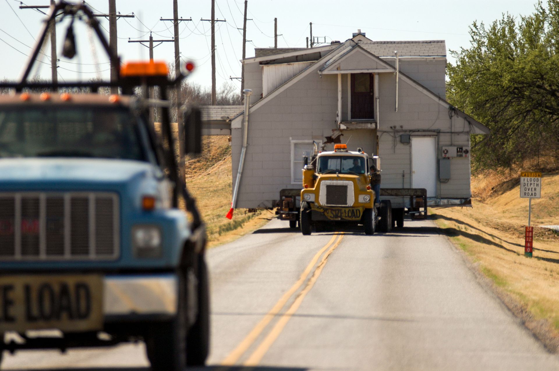 Oversize load structural house relocator with a two-storey home on a highway. Oversize load structural house relocator with a two-storey home on a highway.