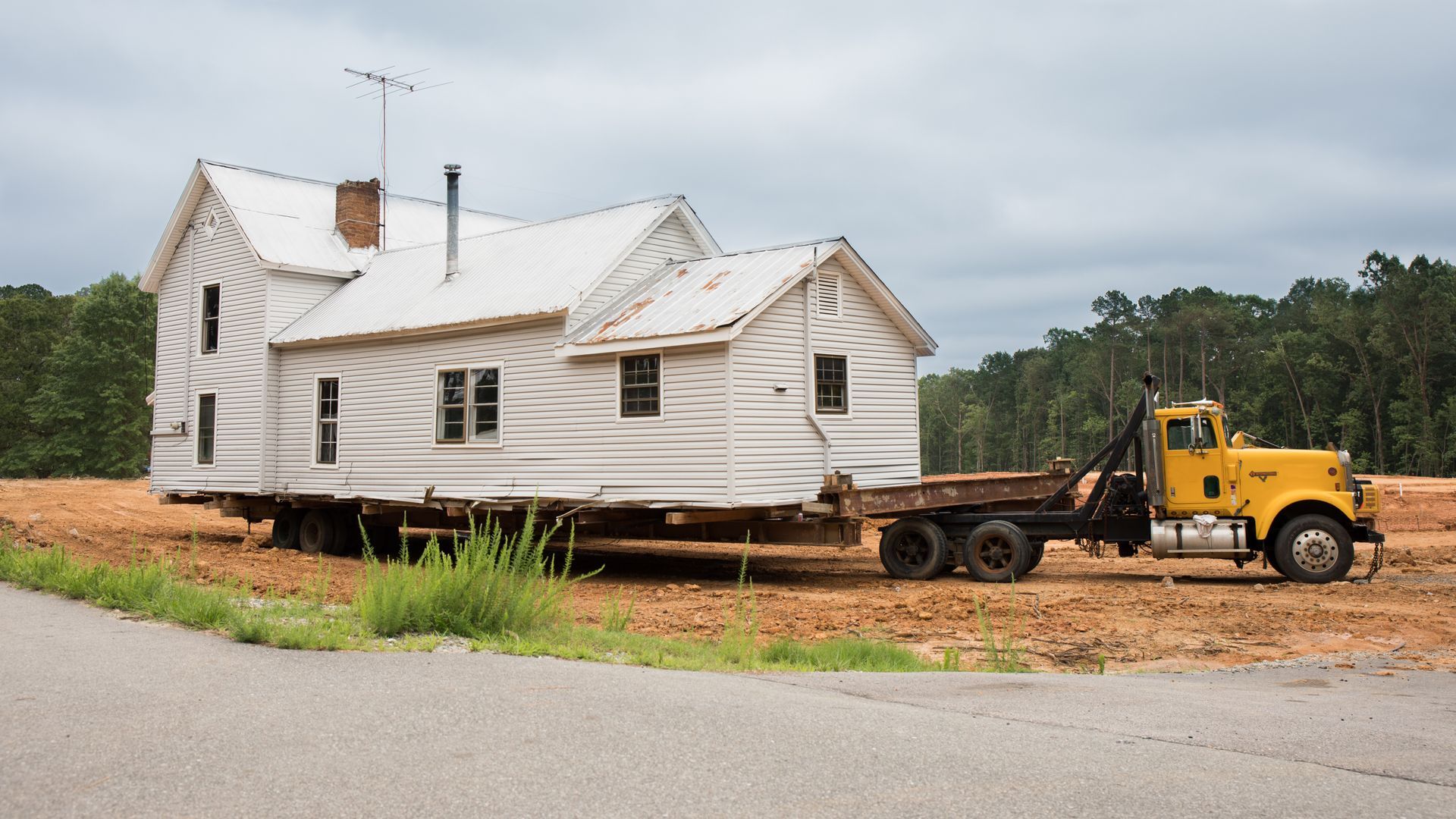 An all-white house being transported on the back of a truck.