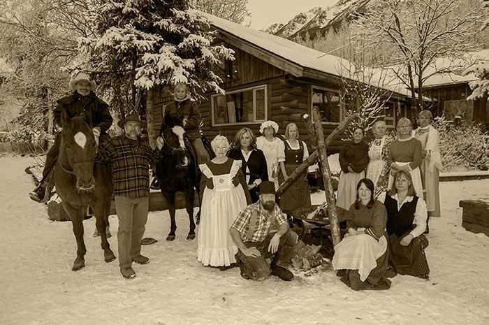A group of people are posing for a picture in front of a cabin in the snow.