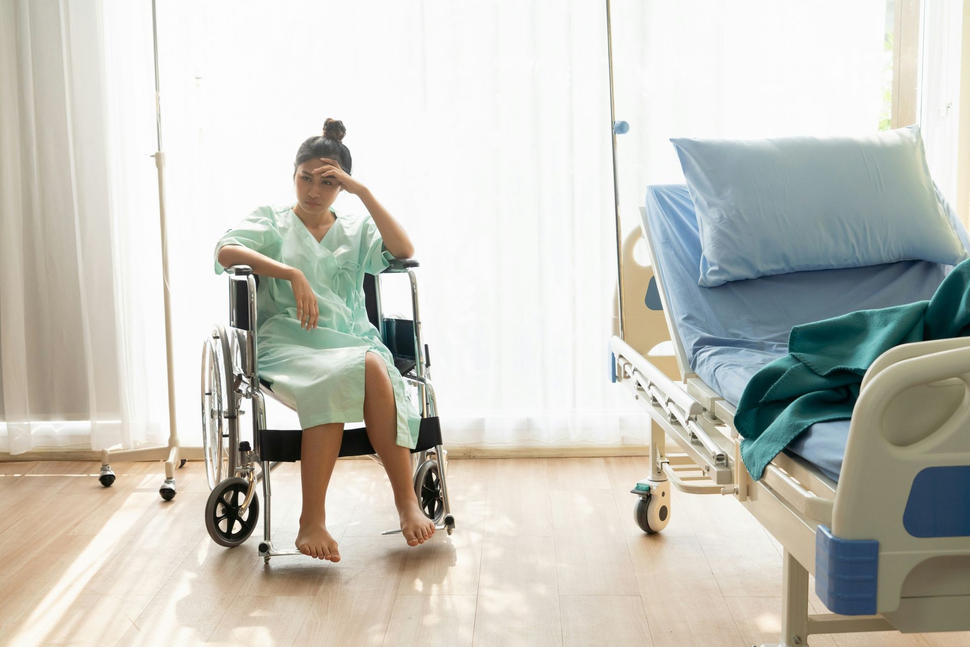 A woman is sitting in a wheelchair in a hospital room.