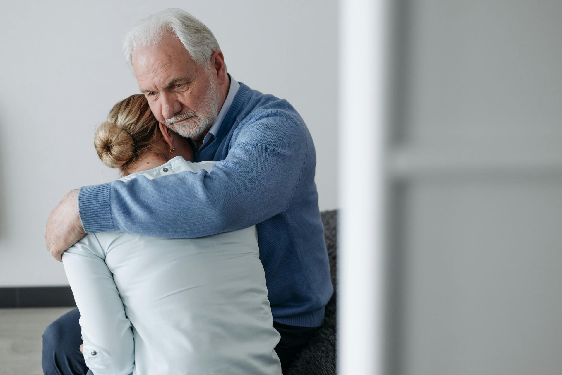 A man and a woman are hugging each other while sitting on a couch.