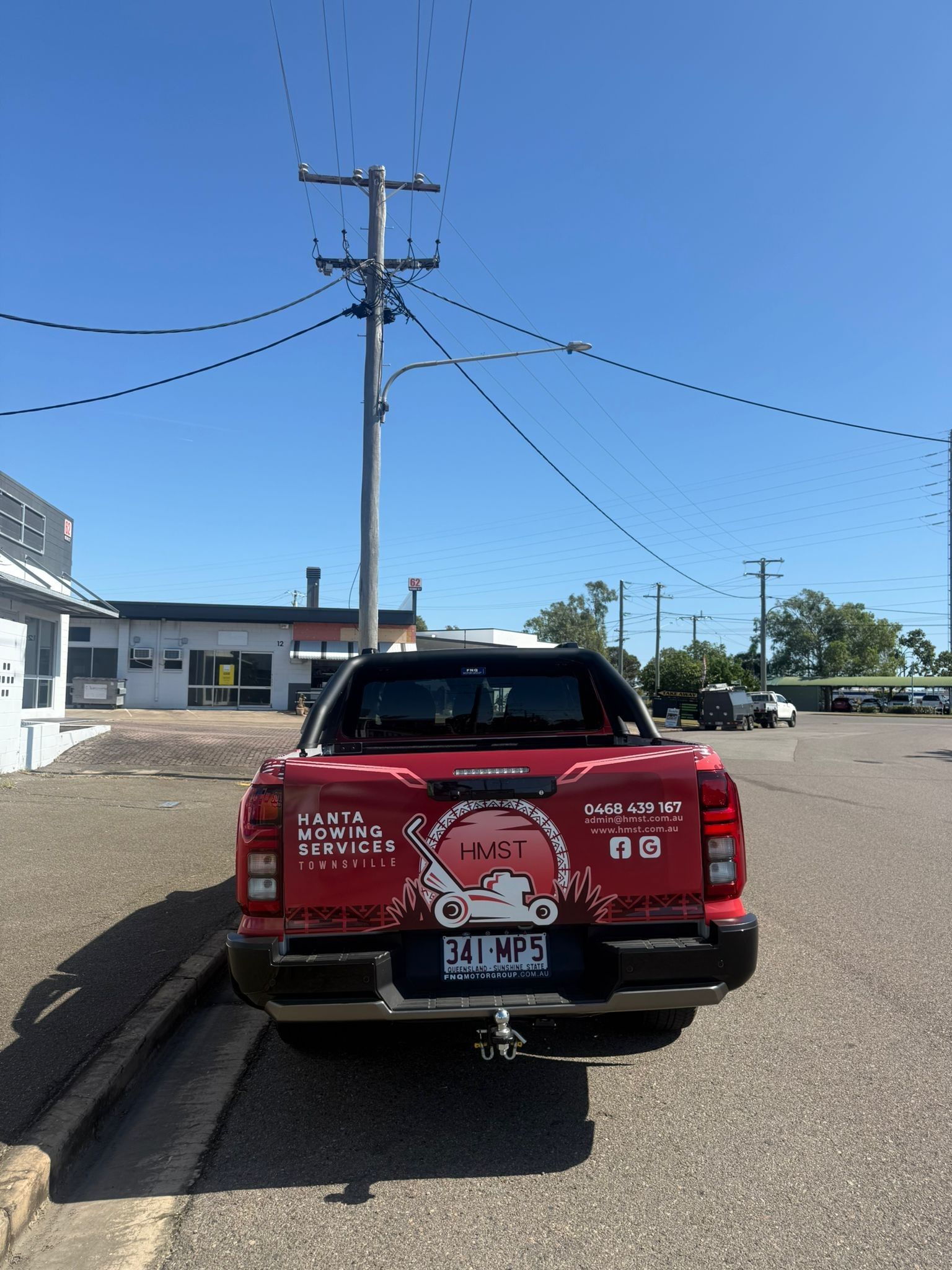 Red Pickup Truck Parked Outside; Sign On The Back; Power Lines Overhead — Hanta Mowing Services Townsville in Kirwan, QLD