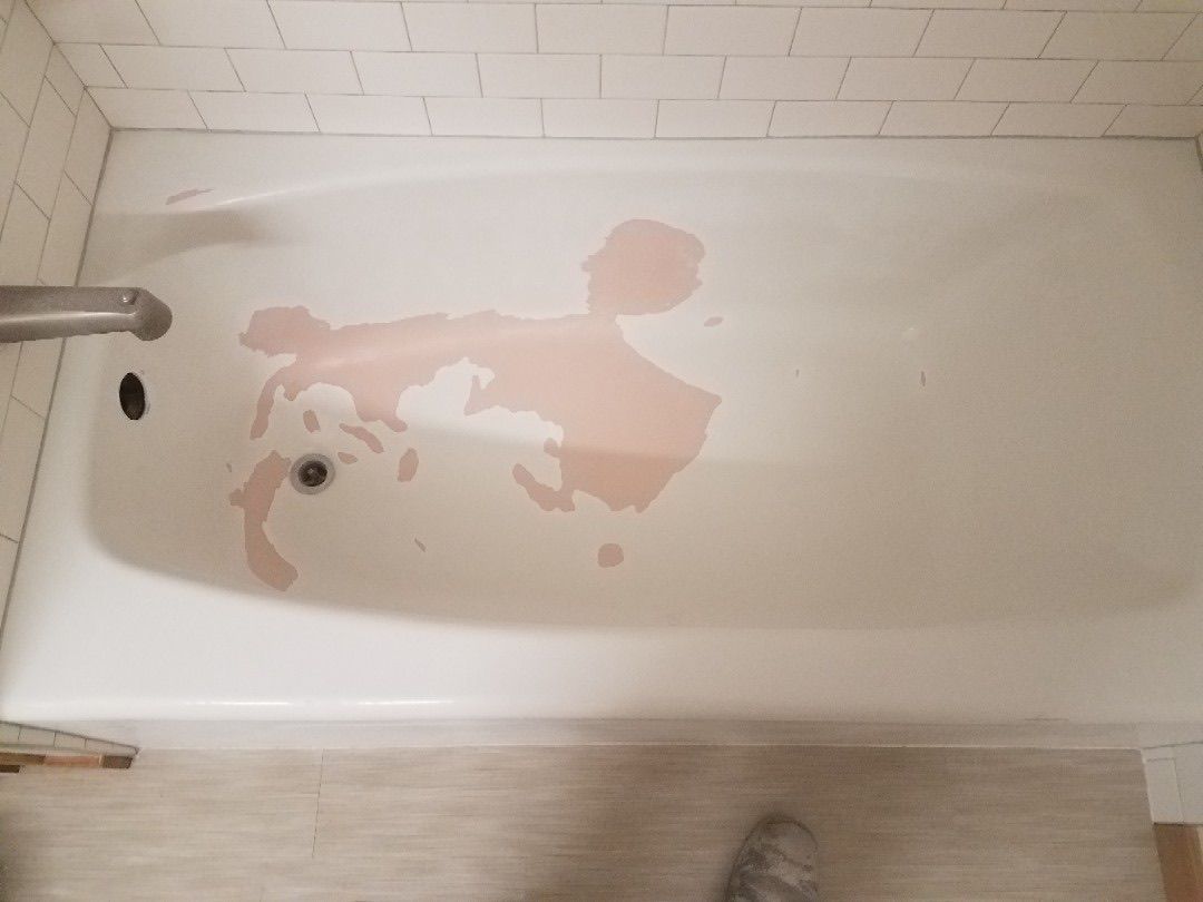 Pink stains in a white bathtub; a chrome faucet is visible. The setting is a bathroom with white tiles.