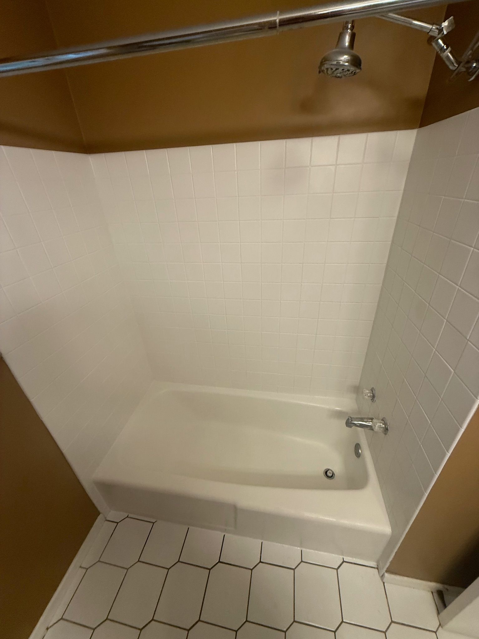 White bathtub and tiled shower with chrome fixtures.