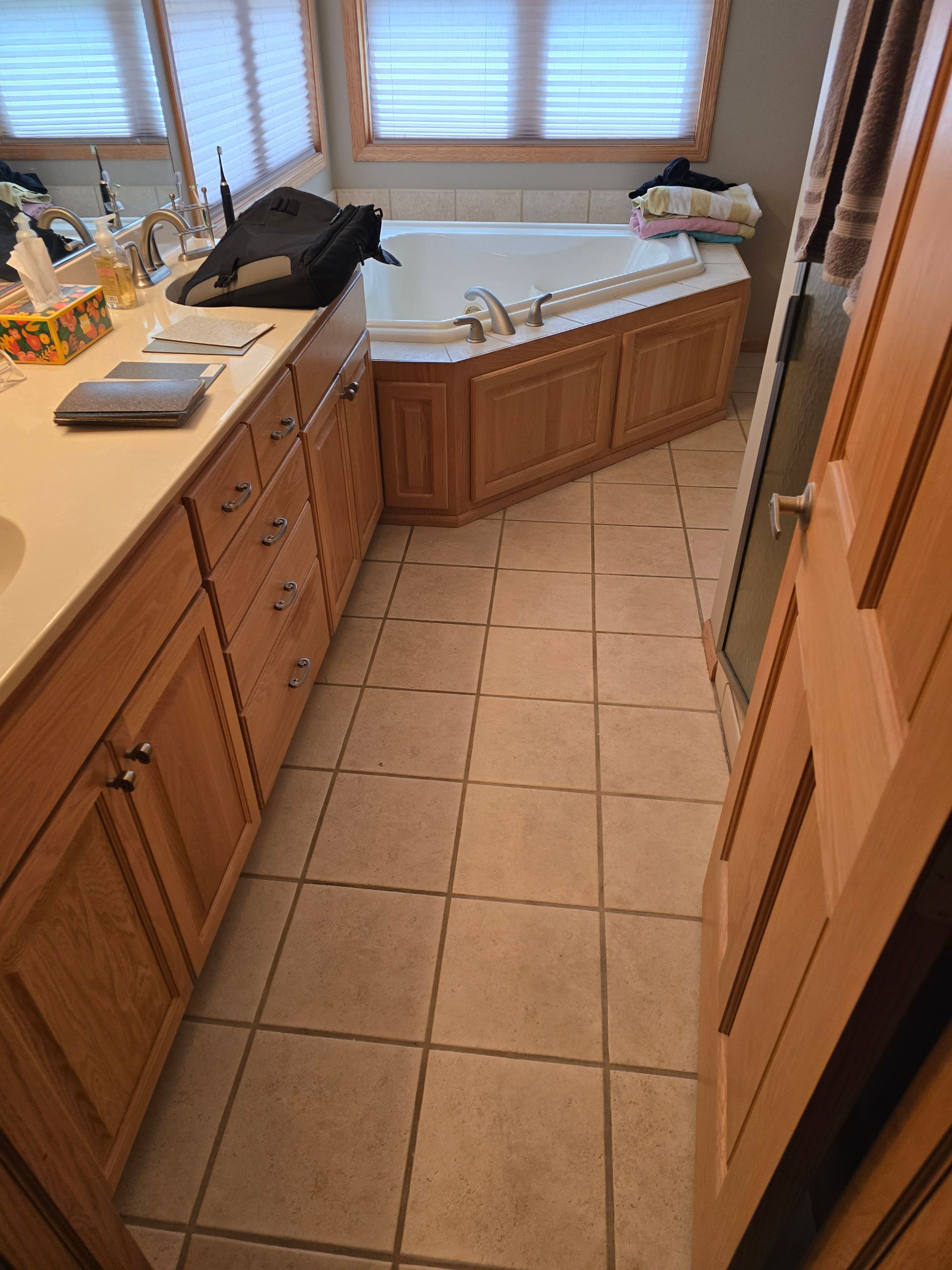 Bathroom with oak cabinets, beige tile floor, and a corner bathtub.