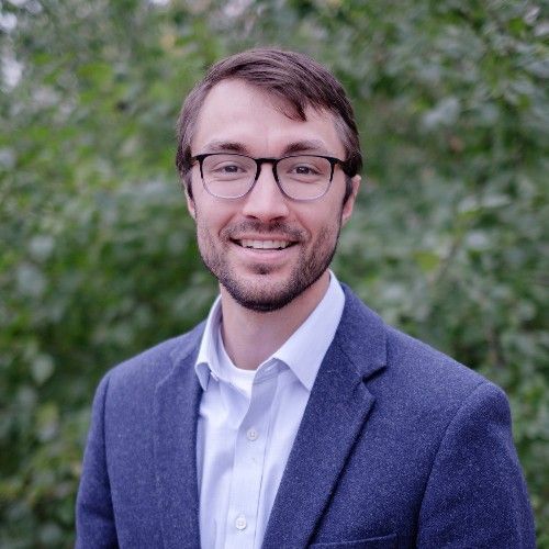 Gray kitchen with large island, marble floors, and modern light fixtures.