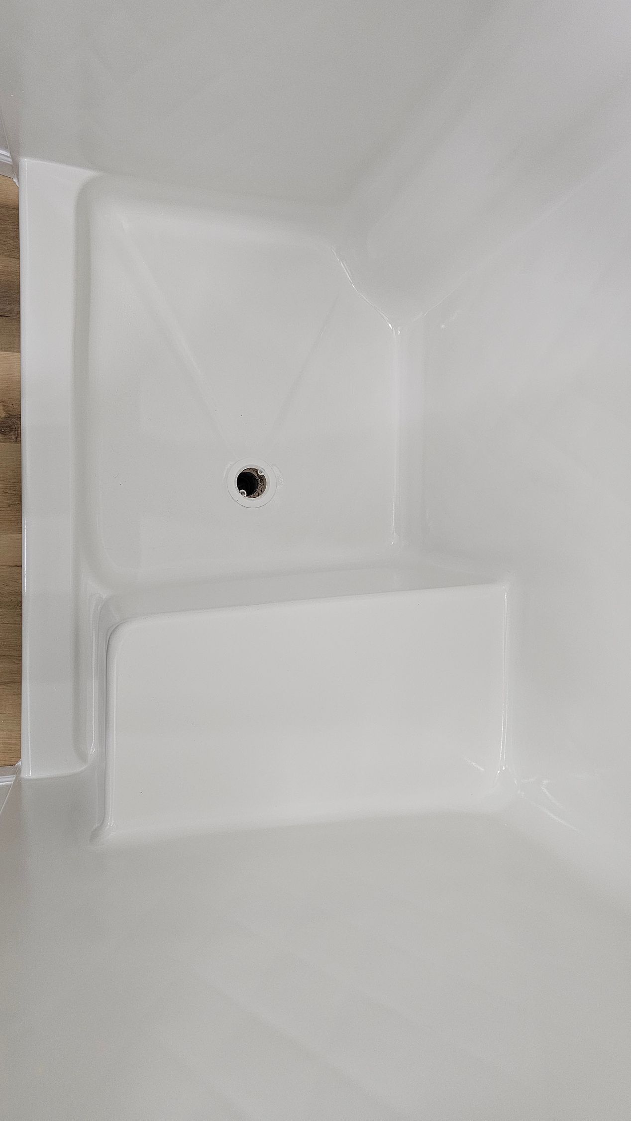 White shower stall with built-in seat and showerhead.