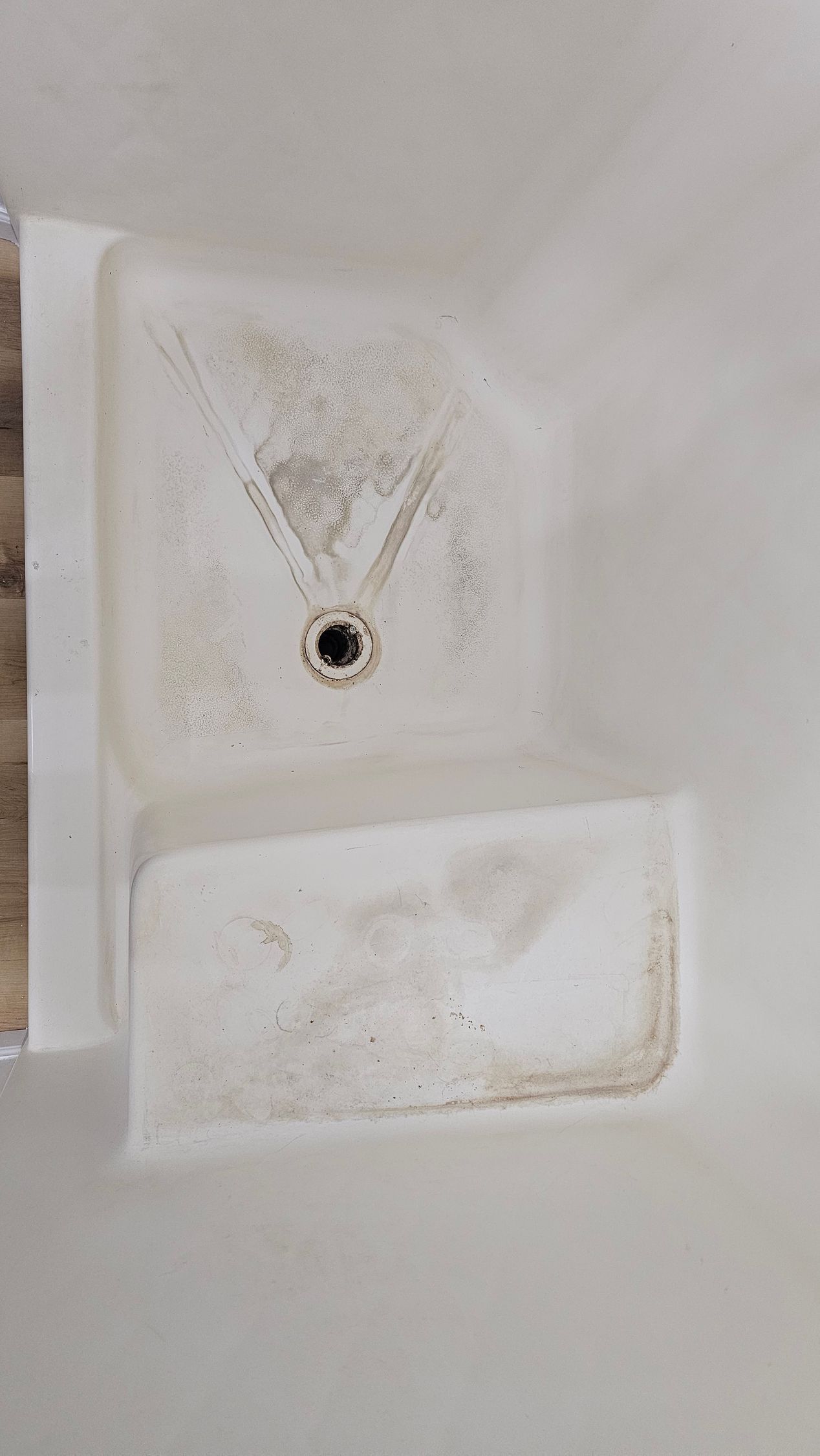 White boat interior with a dirty shower base and drain.
