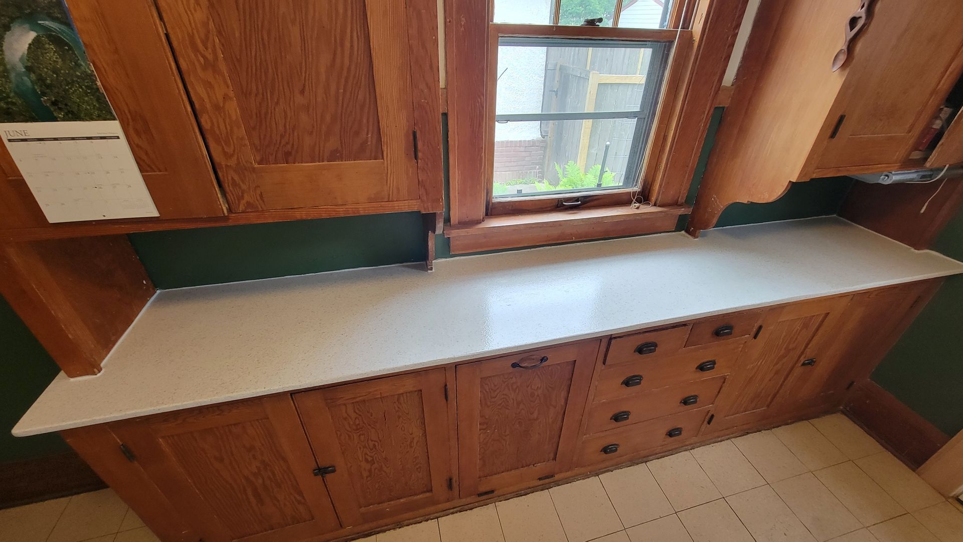 Wooden cabinetry with a white countertop and window.