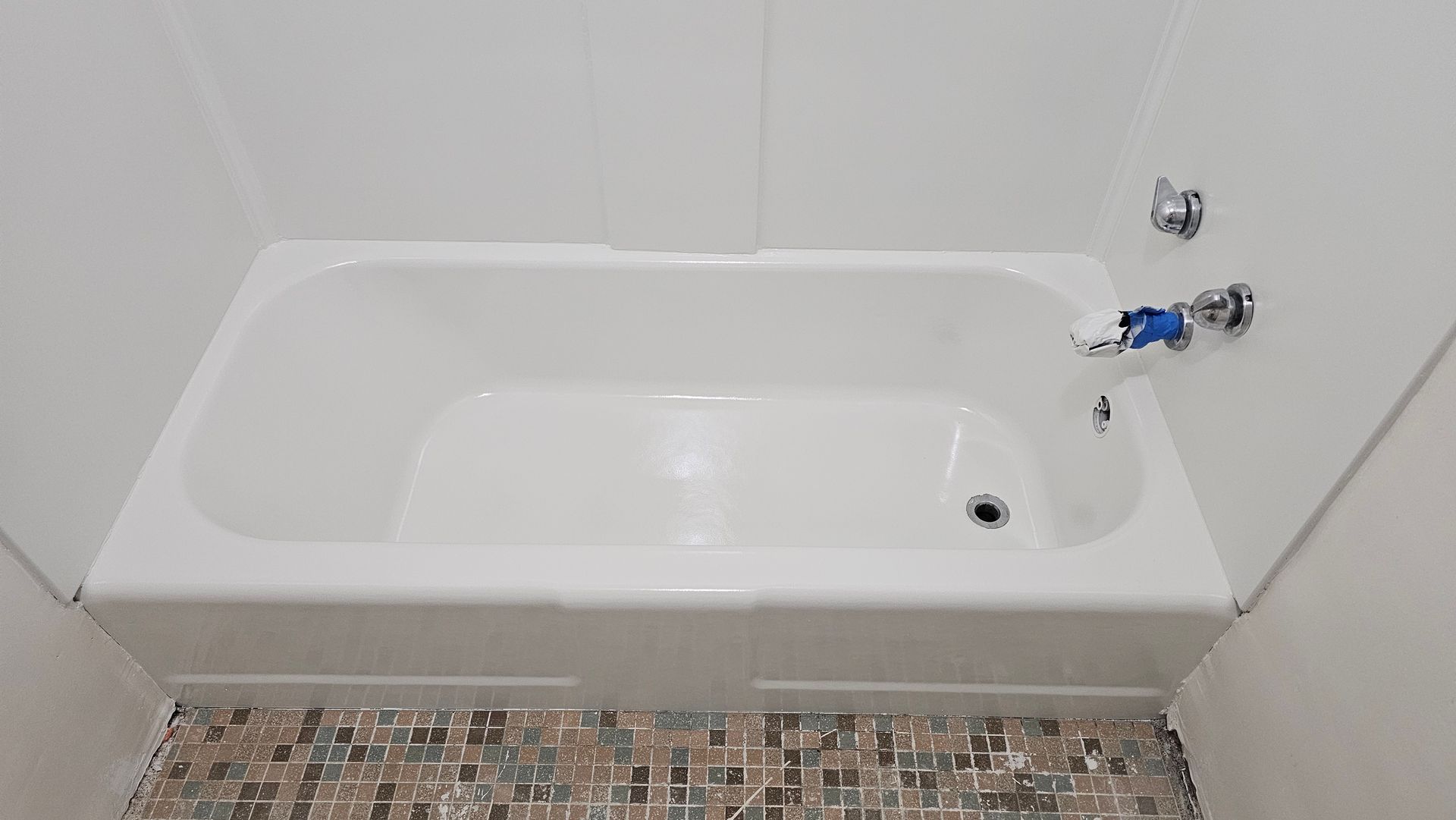 White bathtub in a tiled enclosure, faucet on the right.