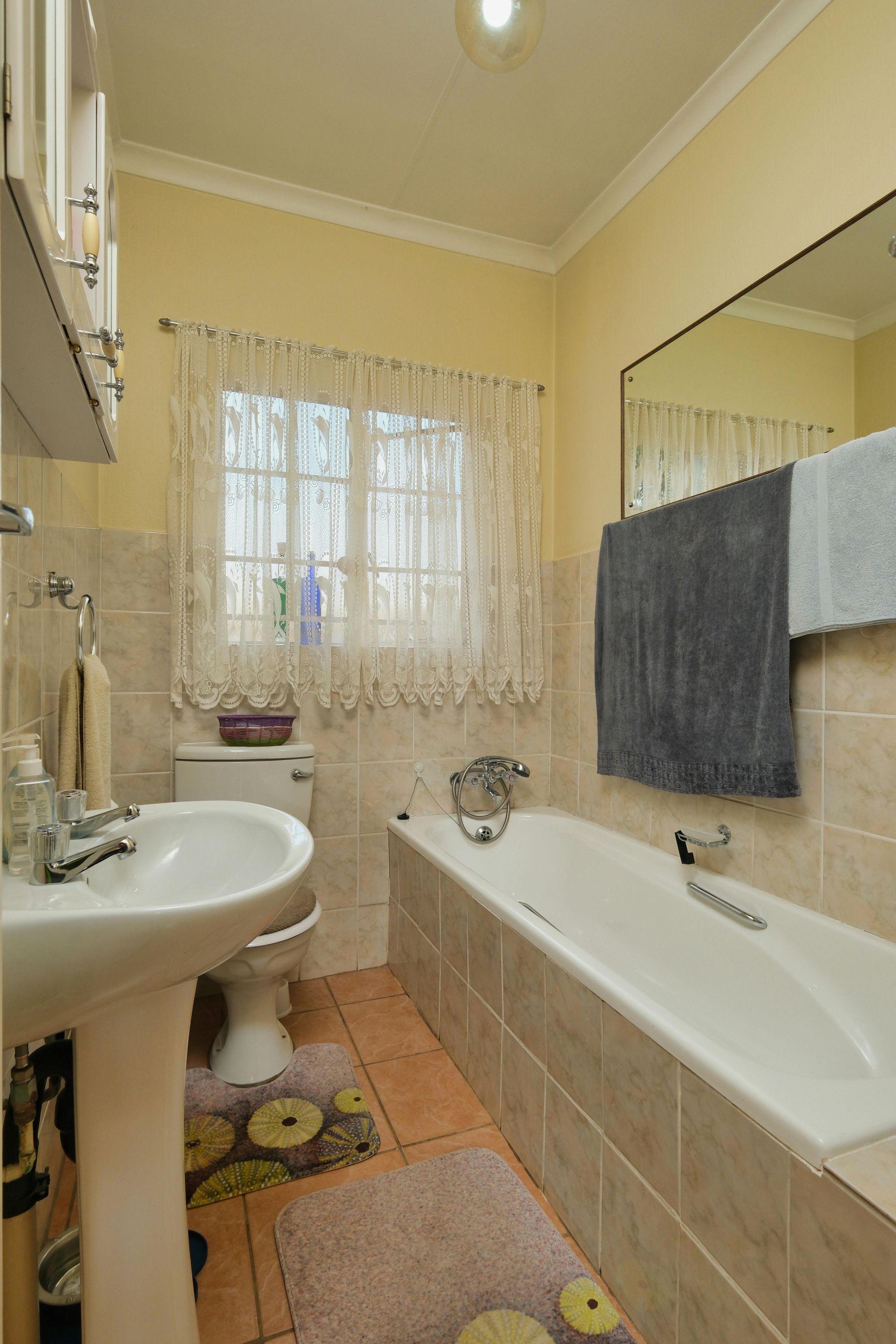Bright white bathroom with a sink, bathtub, and towel warmer.
