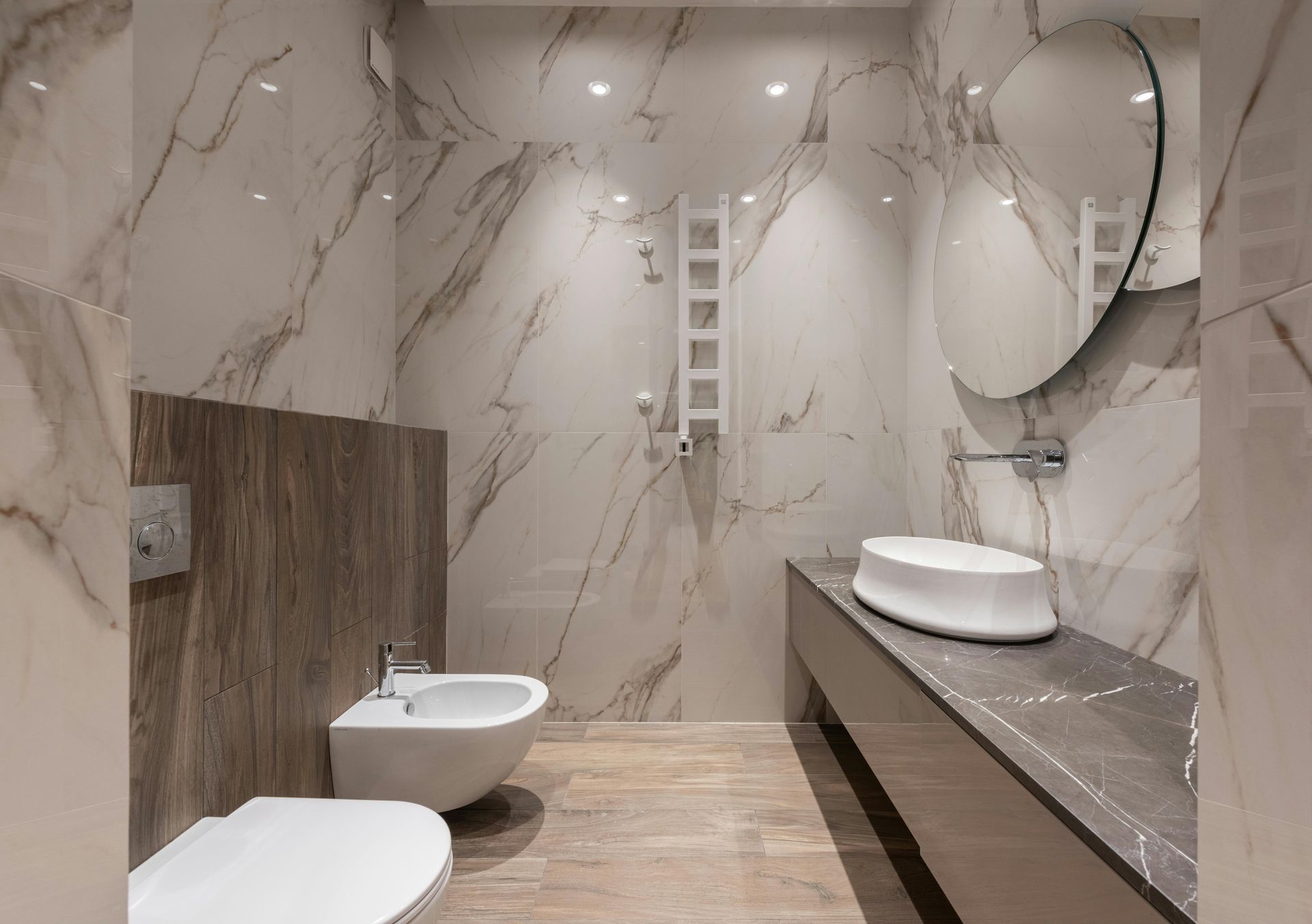 Modern bathroom with marble-look walls, a white sink, toilet, and bidet.