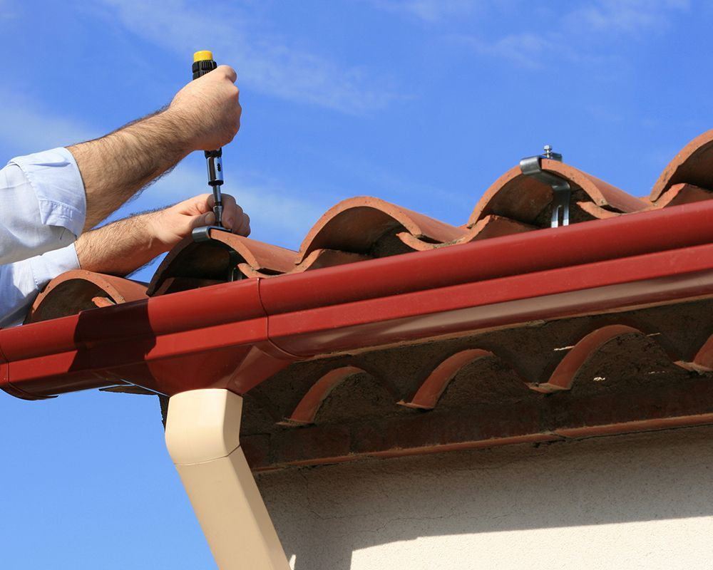 Roofing specialist from Unity Construction Inc. installing a rain gutter on a roof in Champaign, IL