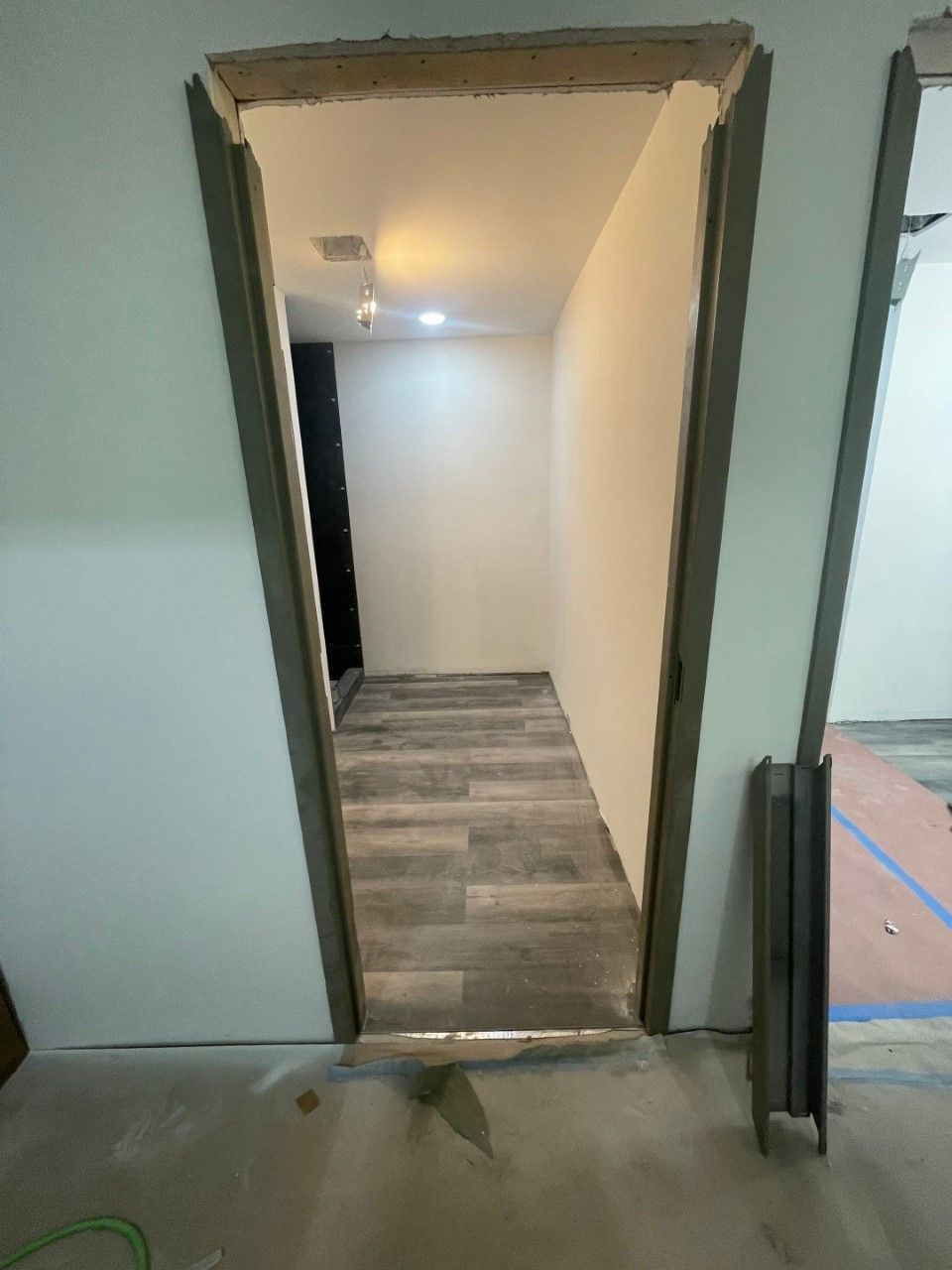 A hallway with a door that is open and a wooden floor.