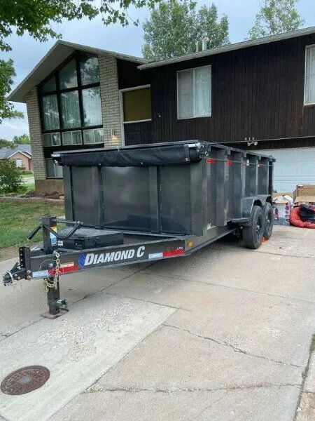 Black Diamond C dump trailer parked on a driveway in front of a house.