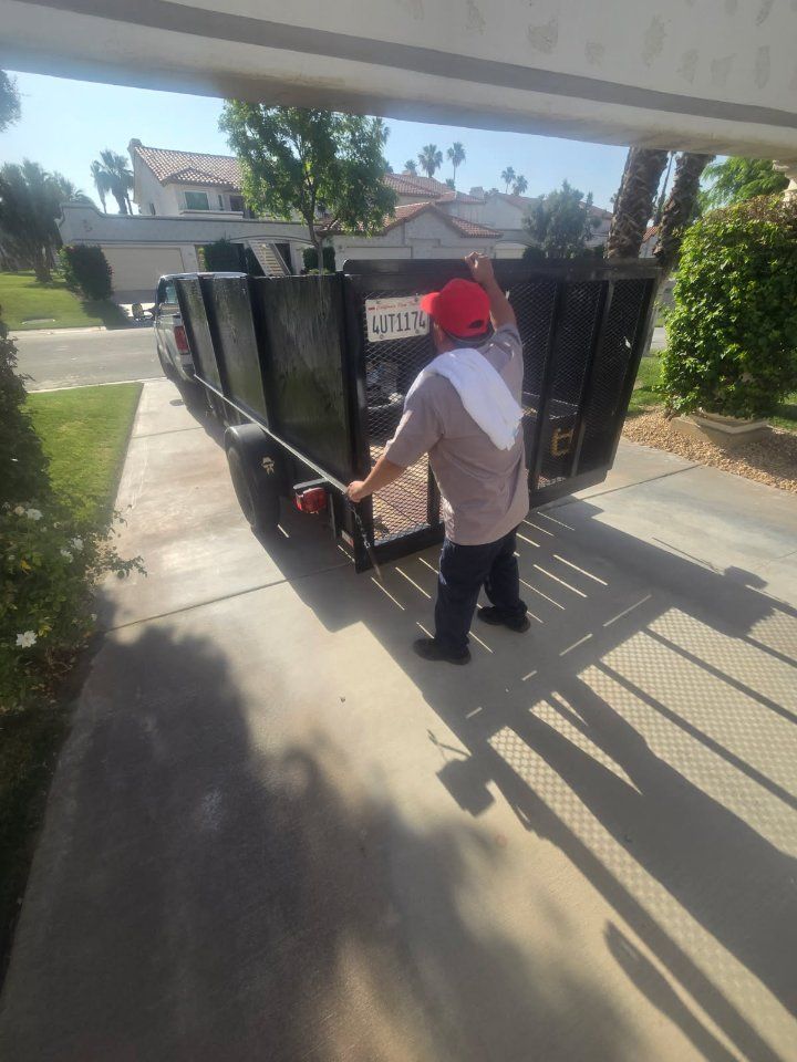 Person in red cap and light shirt pulls up the tailgate of a black truck bed on a driveway.