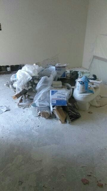 Pile of construction debris and toilet in an unfinished room.
