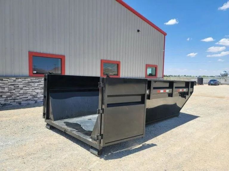 Black industrial dumpster with open door, outdoors in front of building.