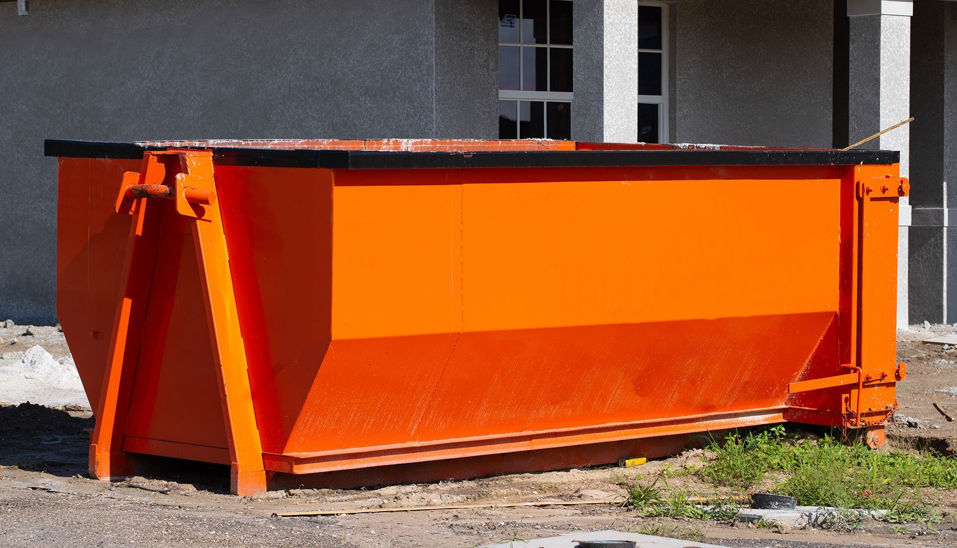 Garbage truck collecting green bins on a narrow city street. Sanitation worker in safety vest.