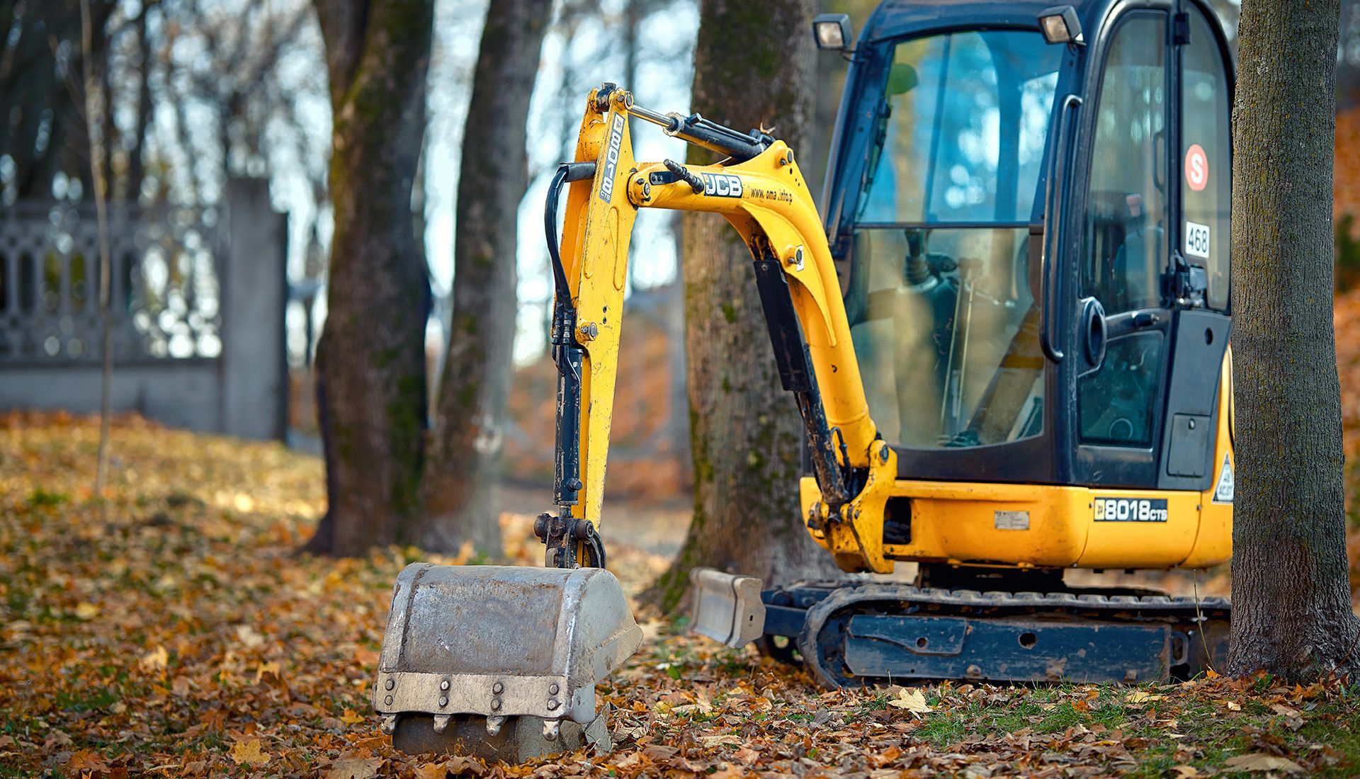 Yellow excavator demolishing a concrete and brick building, creating dust.