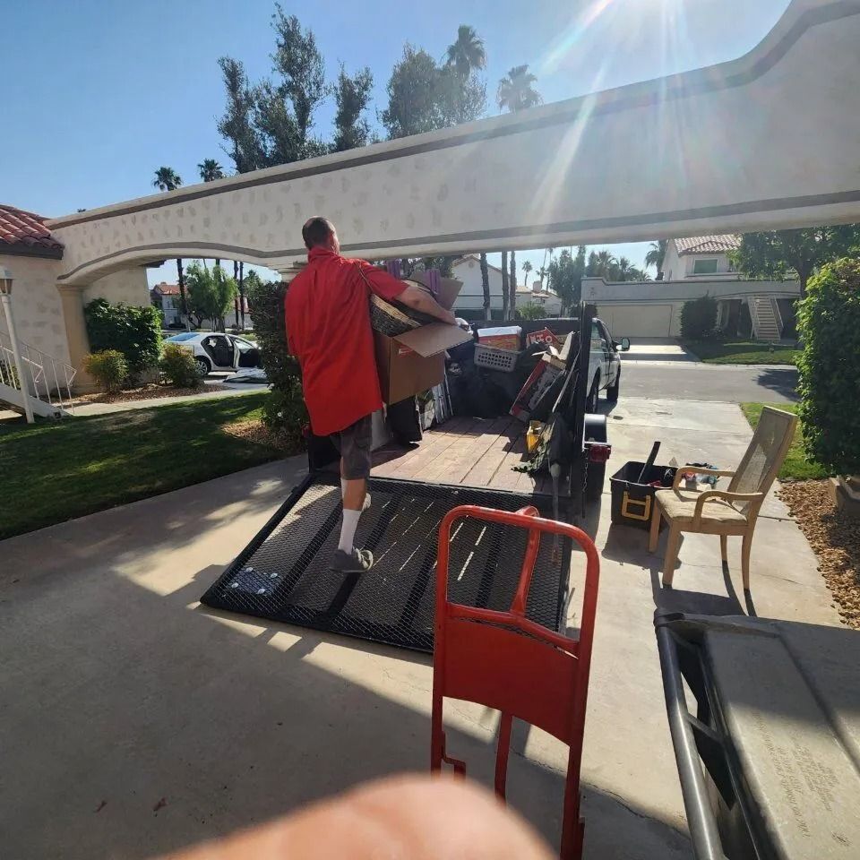 Man loading boxes into a trailer on a sunny day.