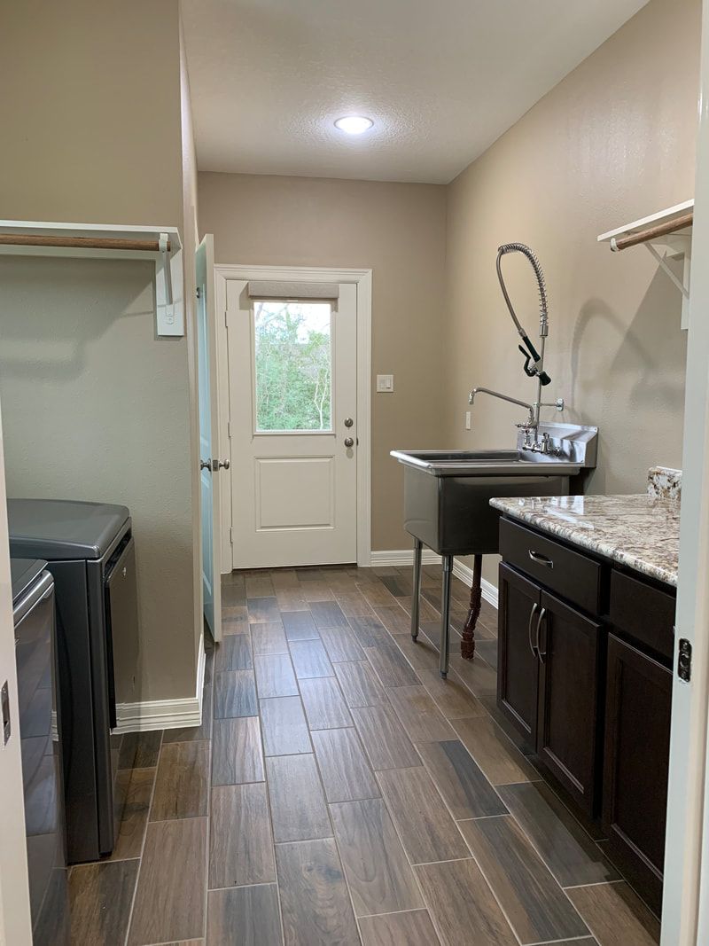 Laundry room with dark cabinets, utility sink, washing machine, and door to the outside.