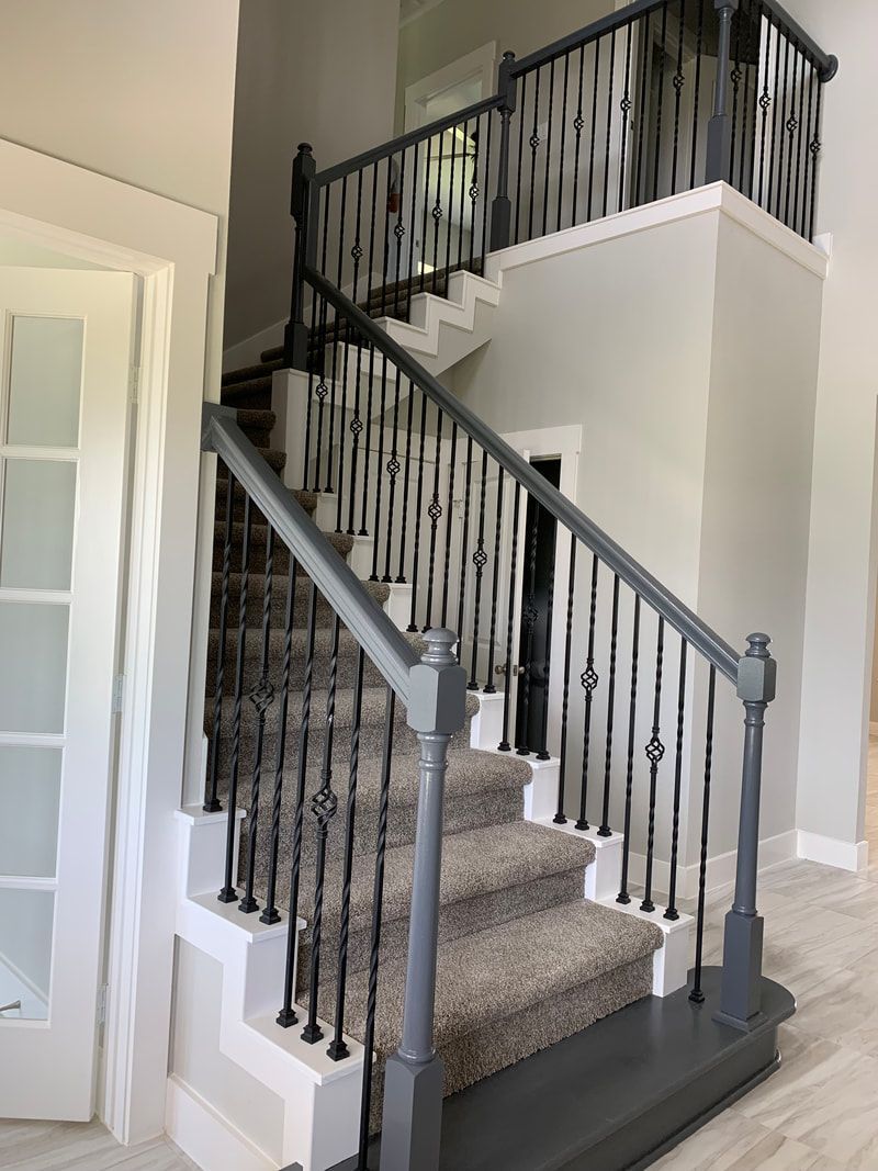 Staircase with gray railing and carpeted steps; white and gray walls.