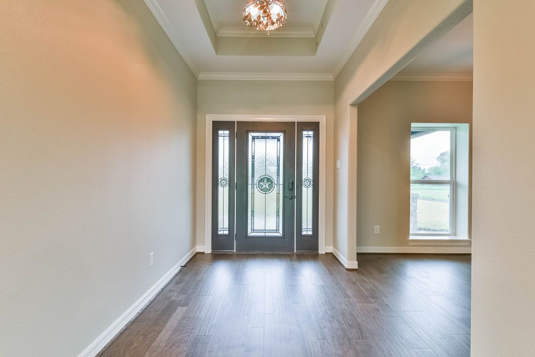 Entryway with dark door, sidelights, and recessed ceiling. Dark wood floor and light walls.