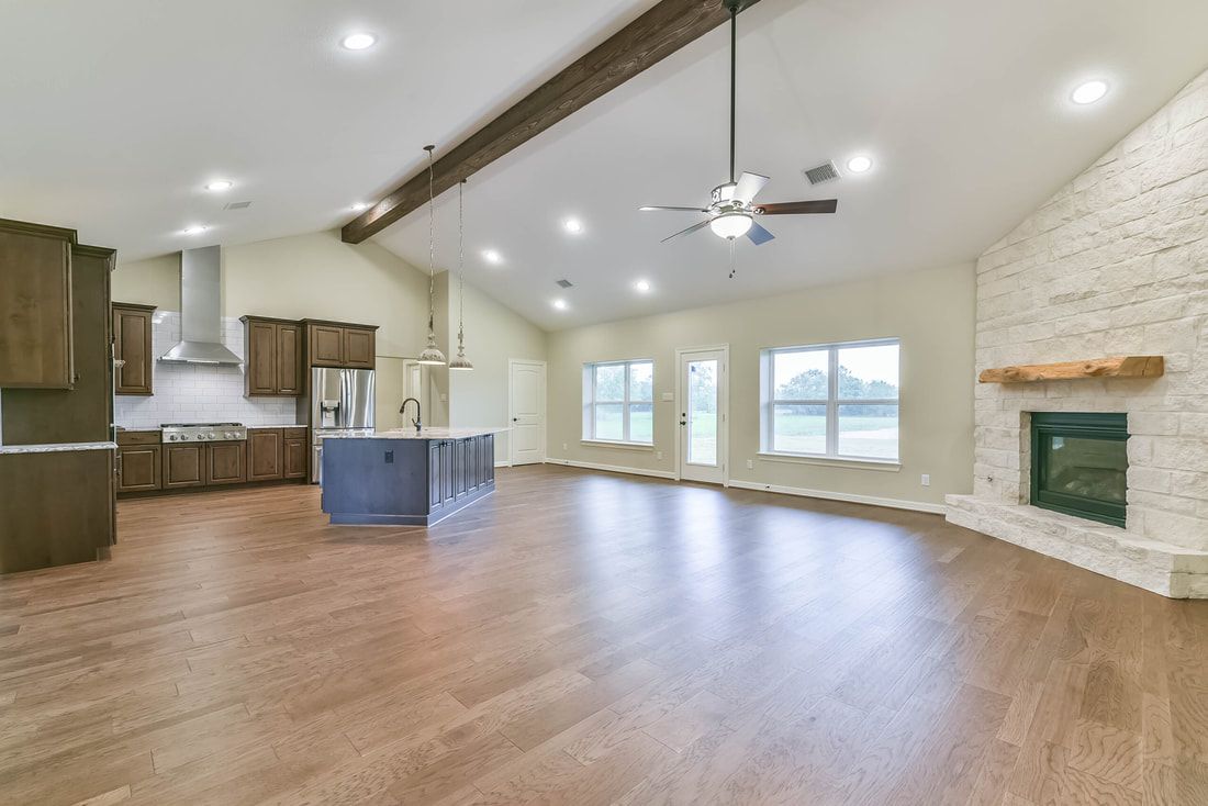 Spacious living room with vaulted ceilings, kitchen, fireplace, and hardwood floors.