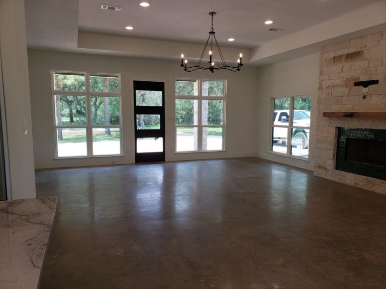 Spacious interior with polished concrete floor, windows, fireplace, and chandelier.